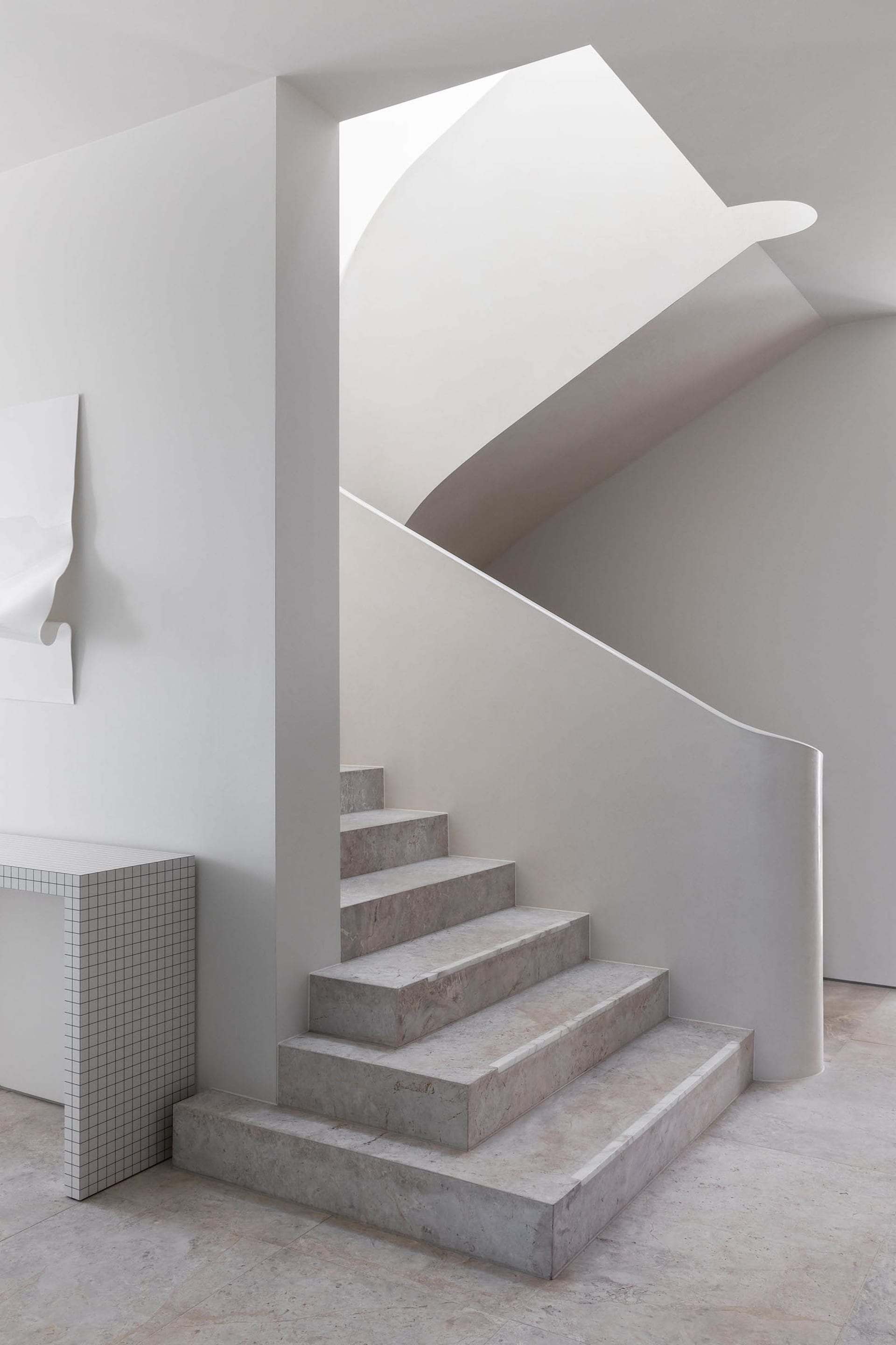 A modern staircase with marble steps in a white building, featuring clean lines and minimalistic design elements, taken during daytime with bright and inviting lighting