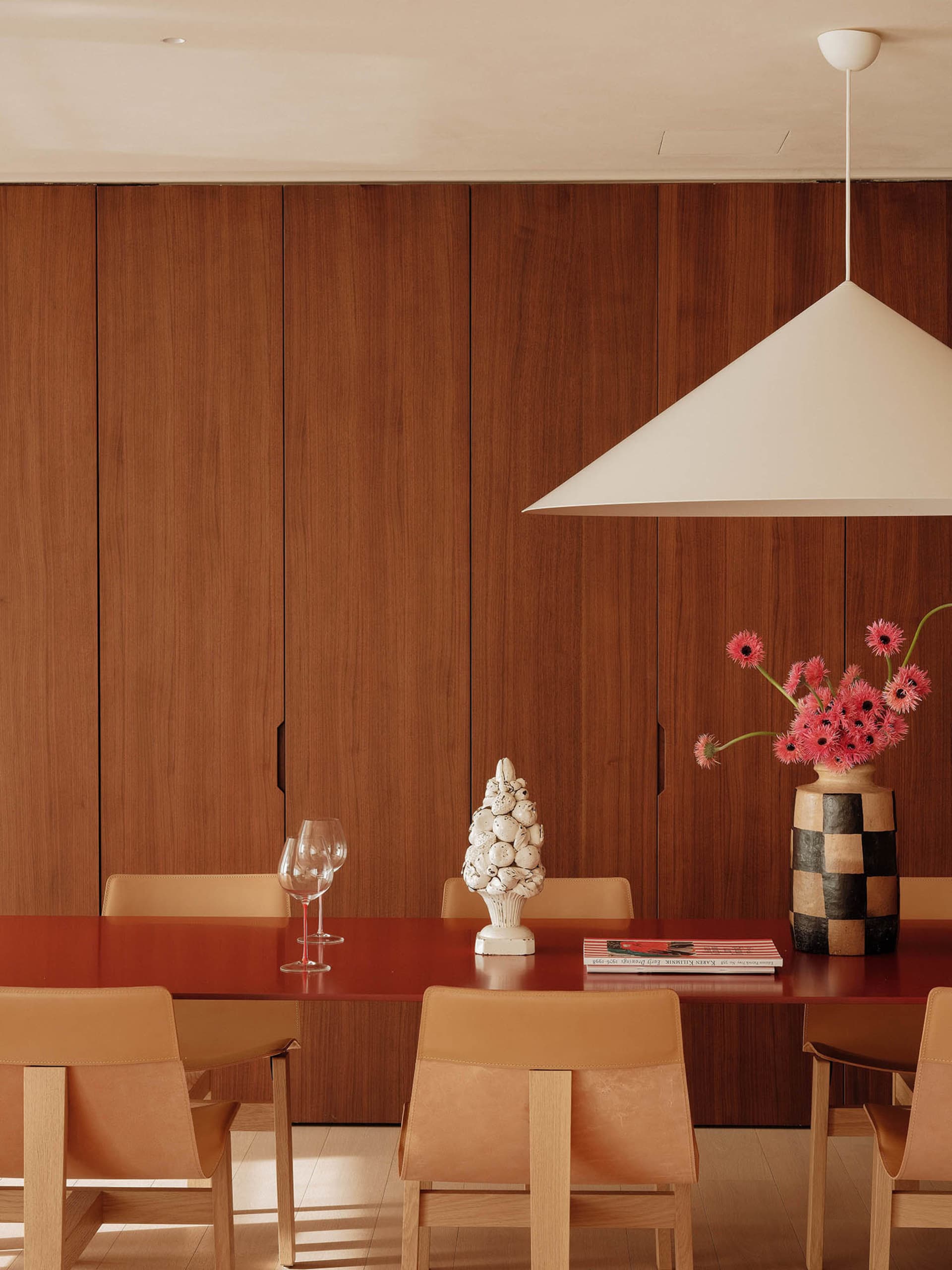 Dining area with a wooden table, chairs, wine glasses, and vases, creating a warm and inviting atmosphere