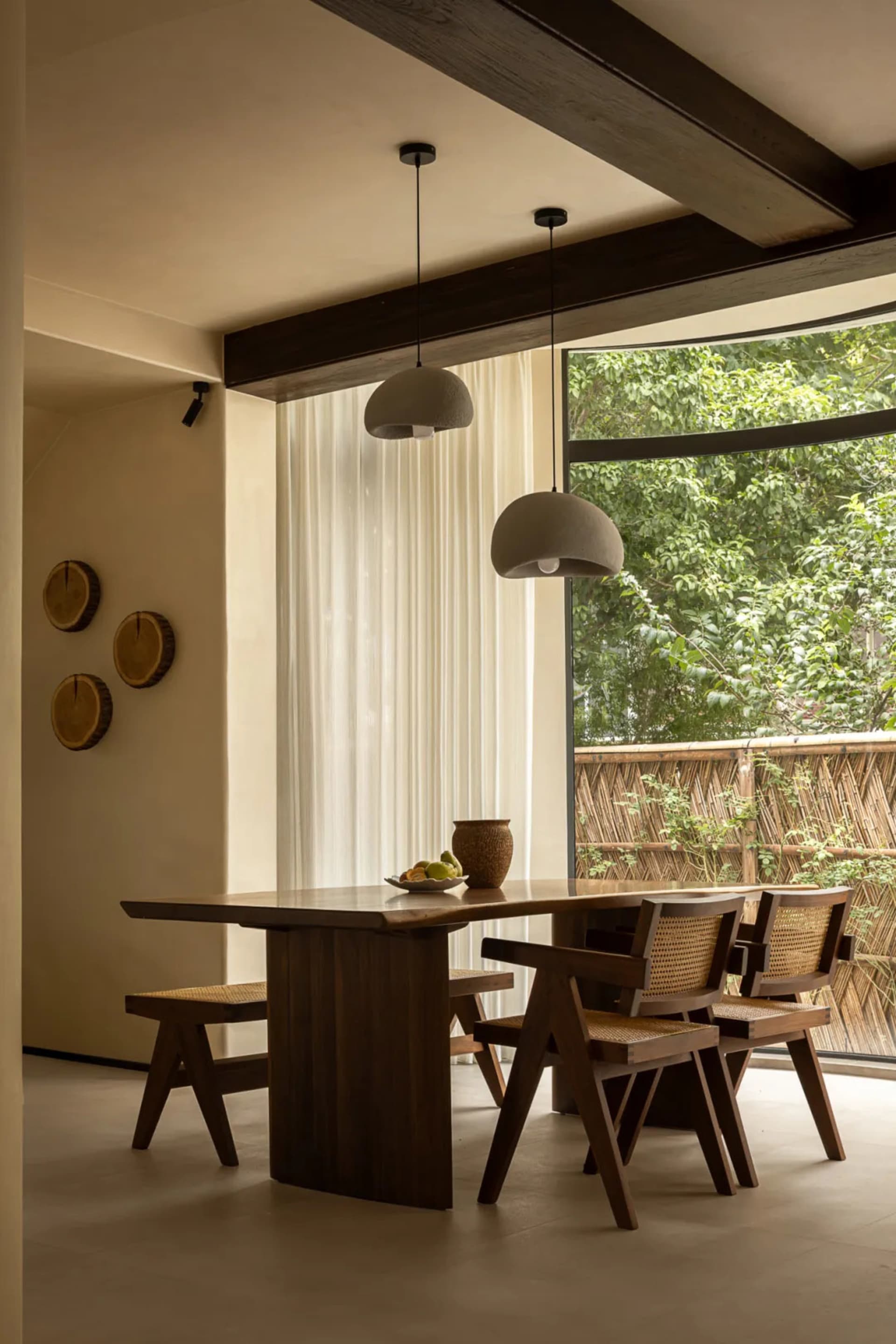 Warm and inviting dining space with a wooden table and chairs, surrounded by natural light and fruit