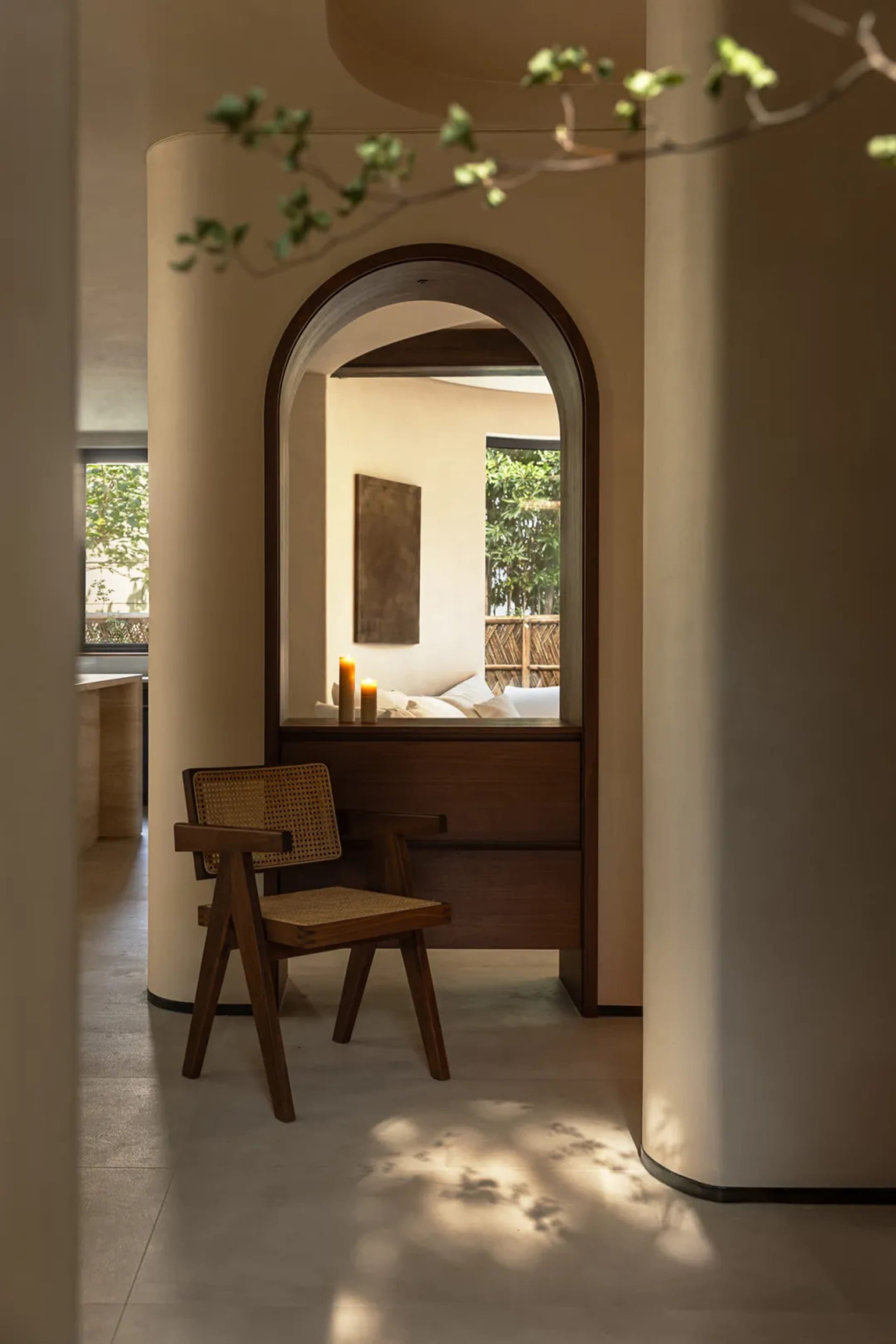 Cozy bedroom with a large mirror, two chairs, a couch, and a potted plant, creating a warm and inviting atmosphere