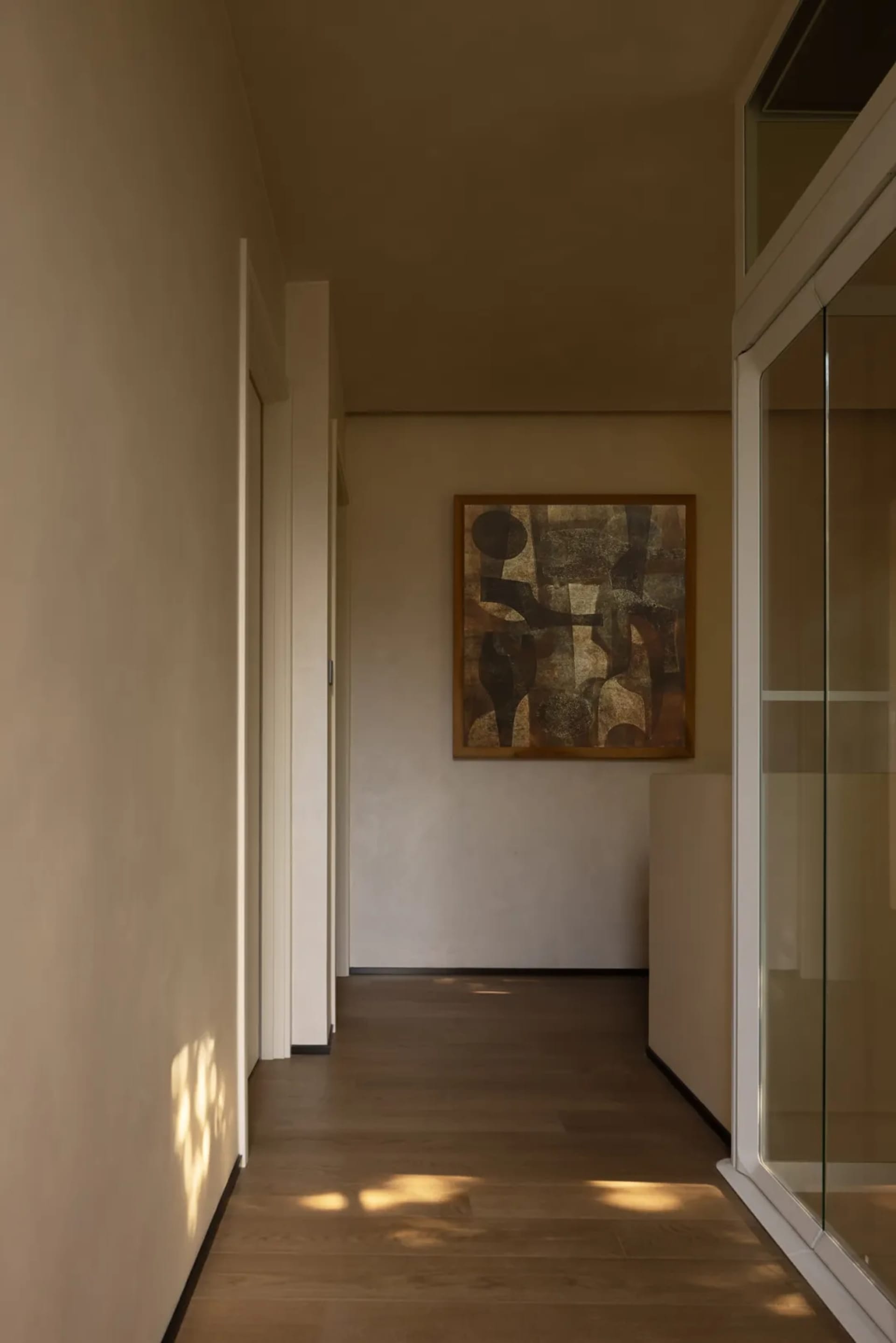 Empty hallway with white walls and wooden floors, giving a clean and minimalist appearance