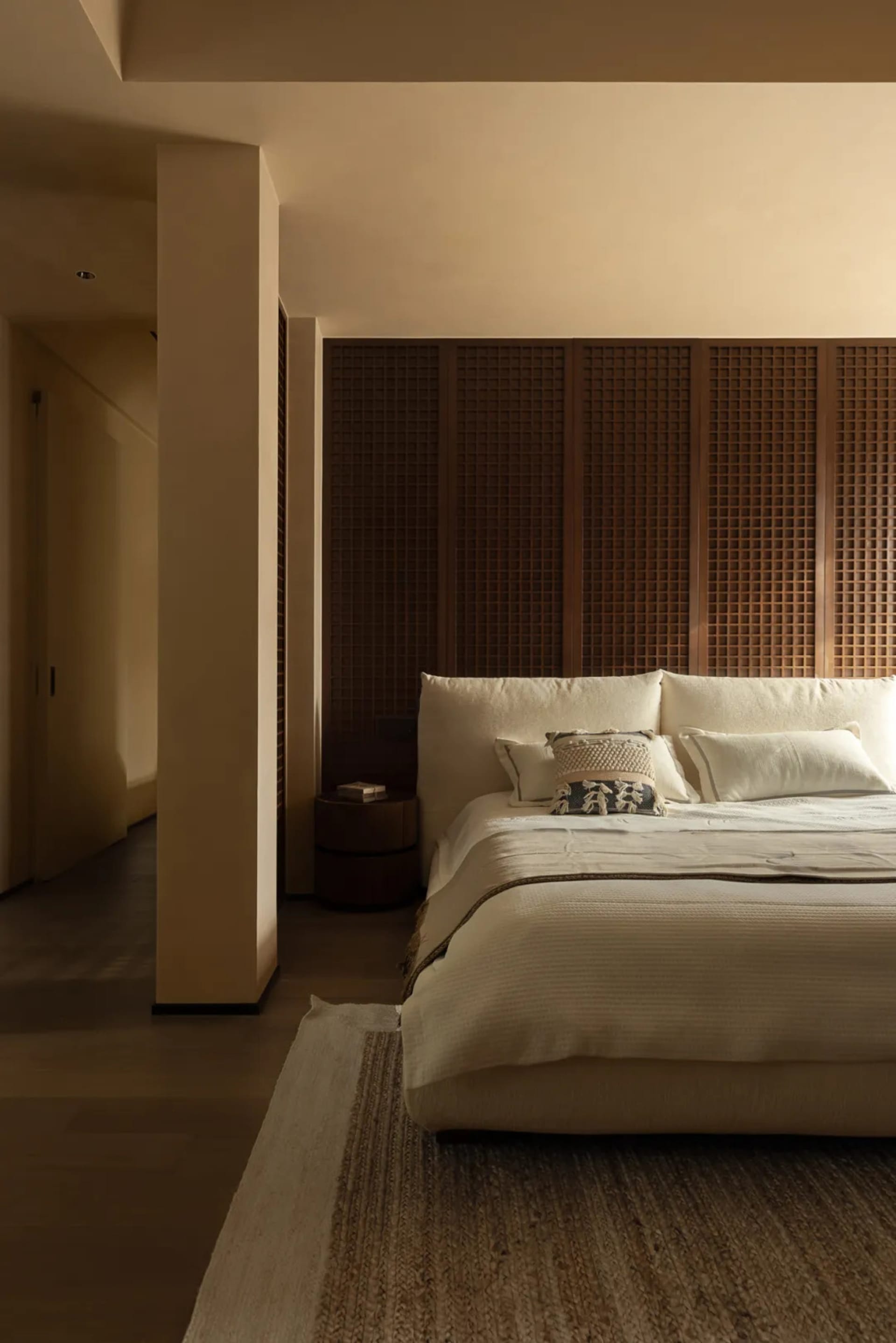A well-lit bedroom with a large white bed, wooden headboard, and two pillows, set in a calm and inviting atmosphere