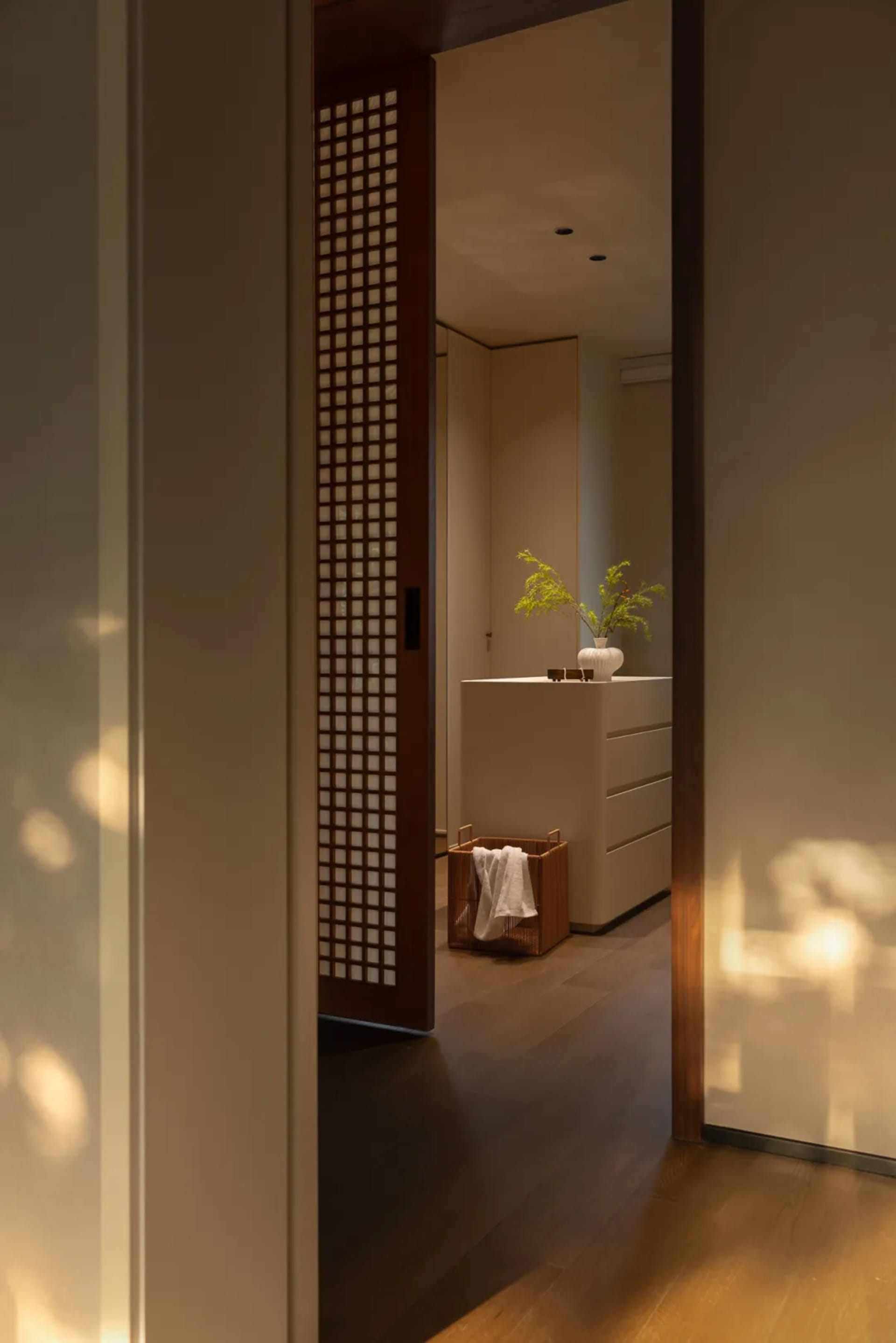 Narrow hallway with wooden flooring and walls, featuring potted plants and a decorative vase, giving a warm and traditional feel