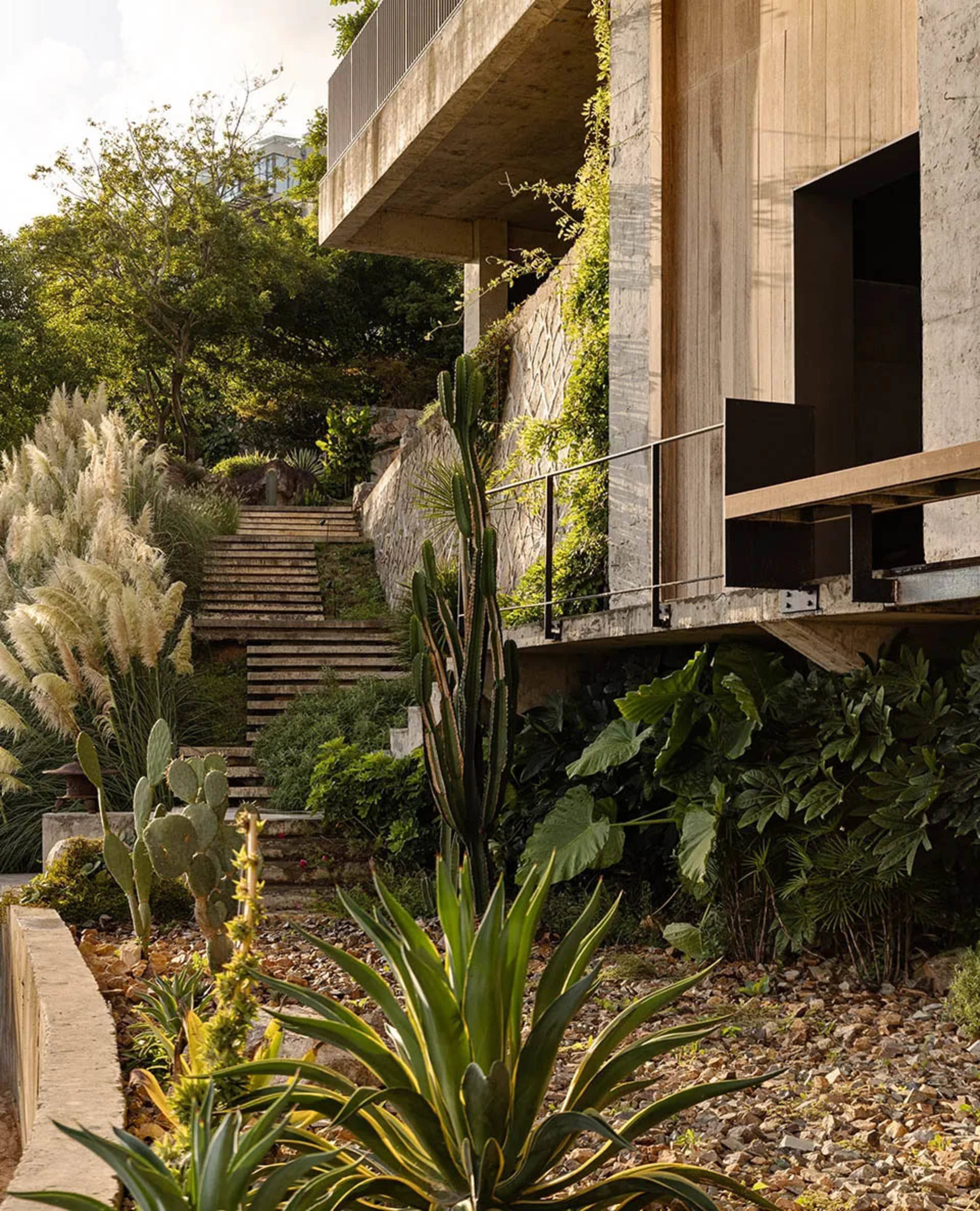 A house with a stone exterior, a large patio area, a staircase, and potted plants, creating a relaxed and inviting atmosphere