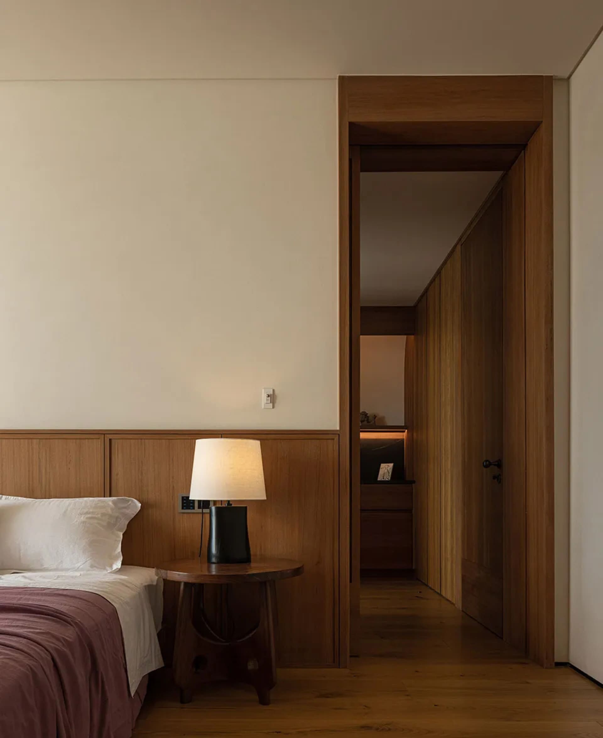 Cozy bedroom with a bed and desk, nightstands, and a doorway to the next room