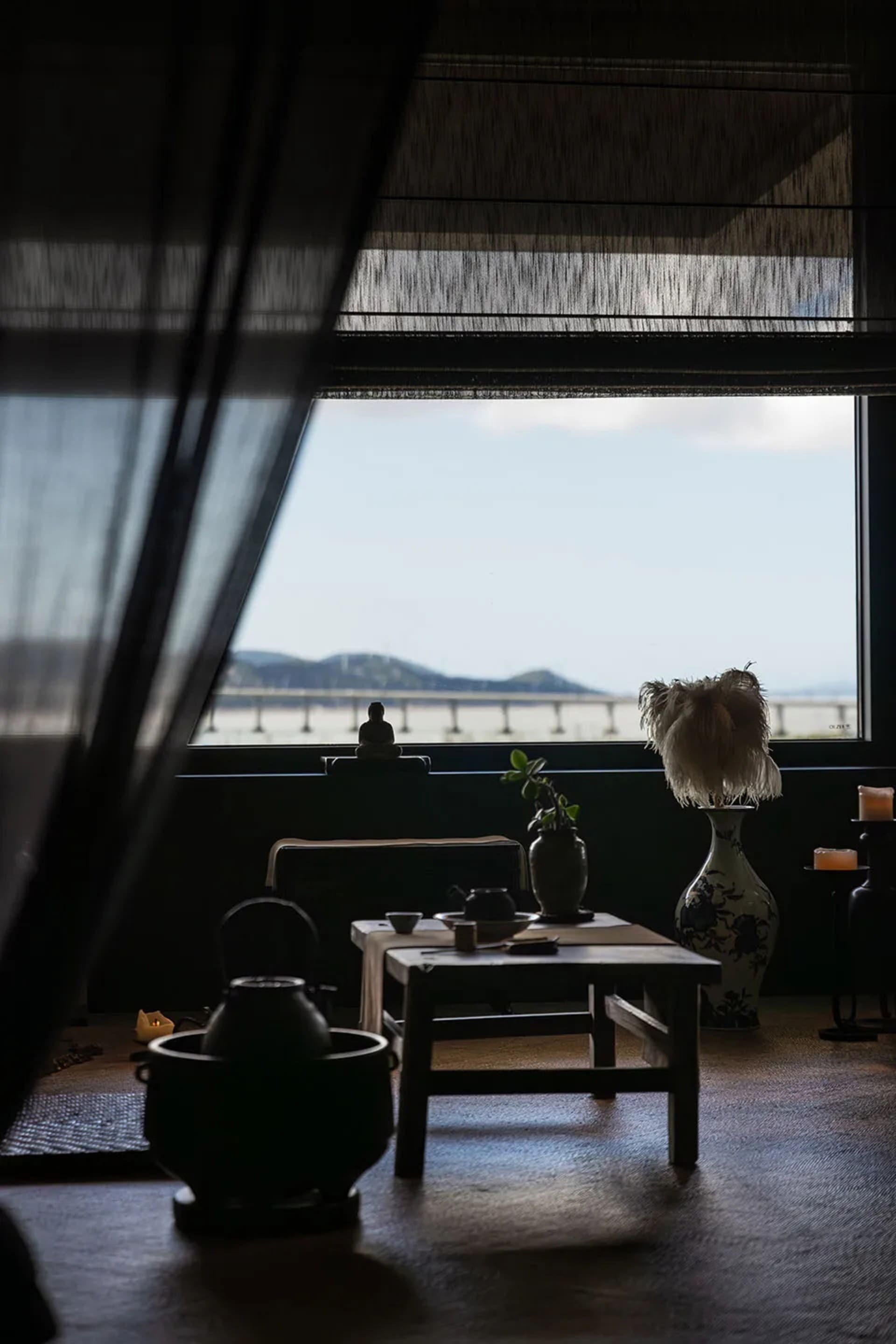 Cozy dining space with a table, chairs, couch, and ocean view, decorated with vases, plants, and a bowl, providing a relaxing atmosphere