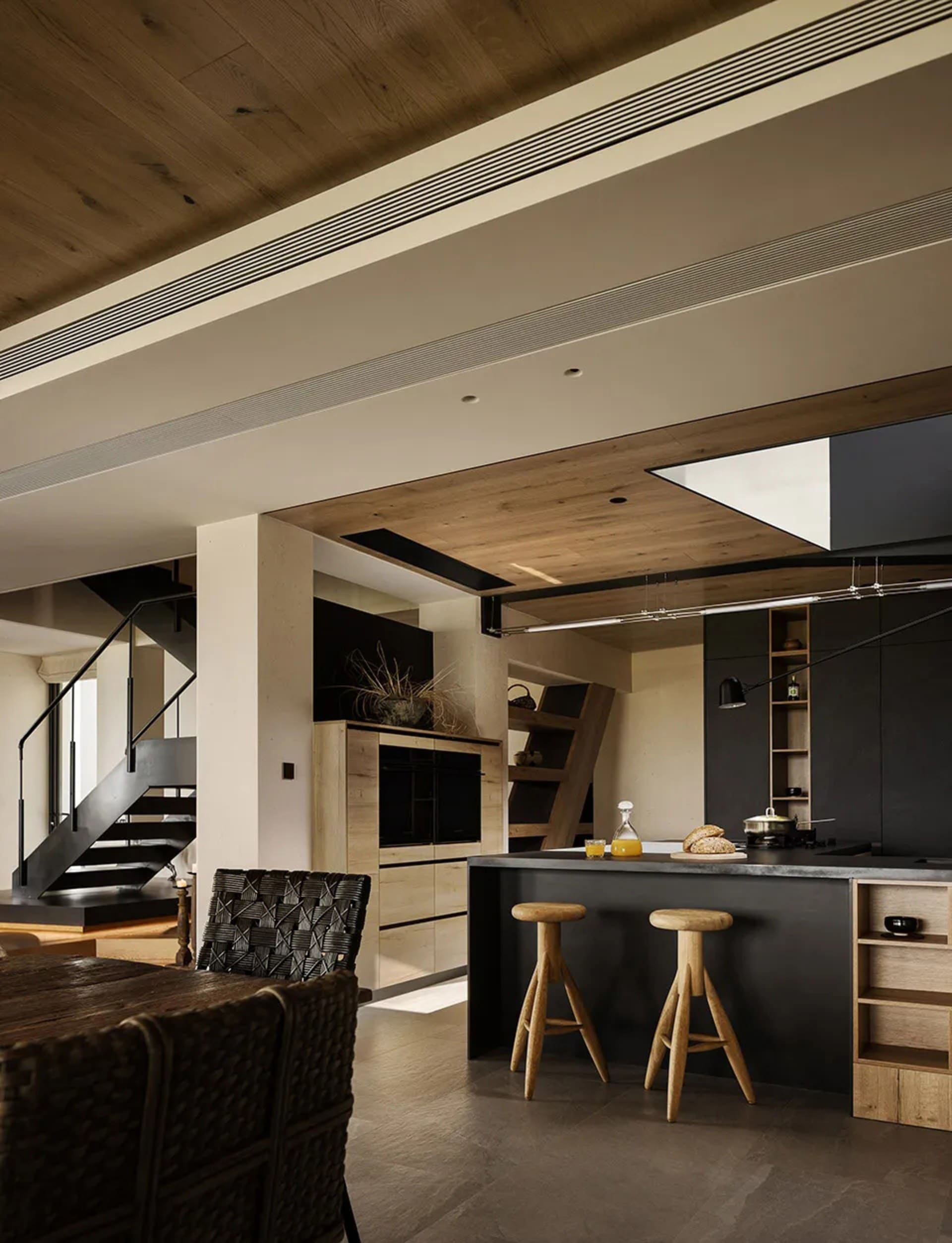 Open living area with wooden floors and walls, featuring a couch, chairs, vases, and a potted plant, with a warm and inviting atmosphere