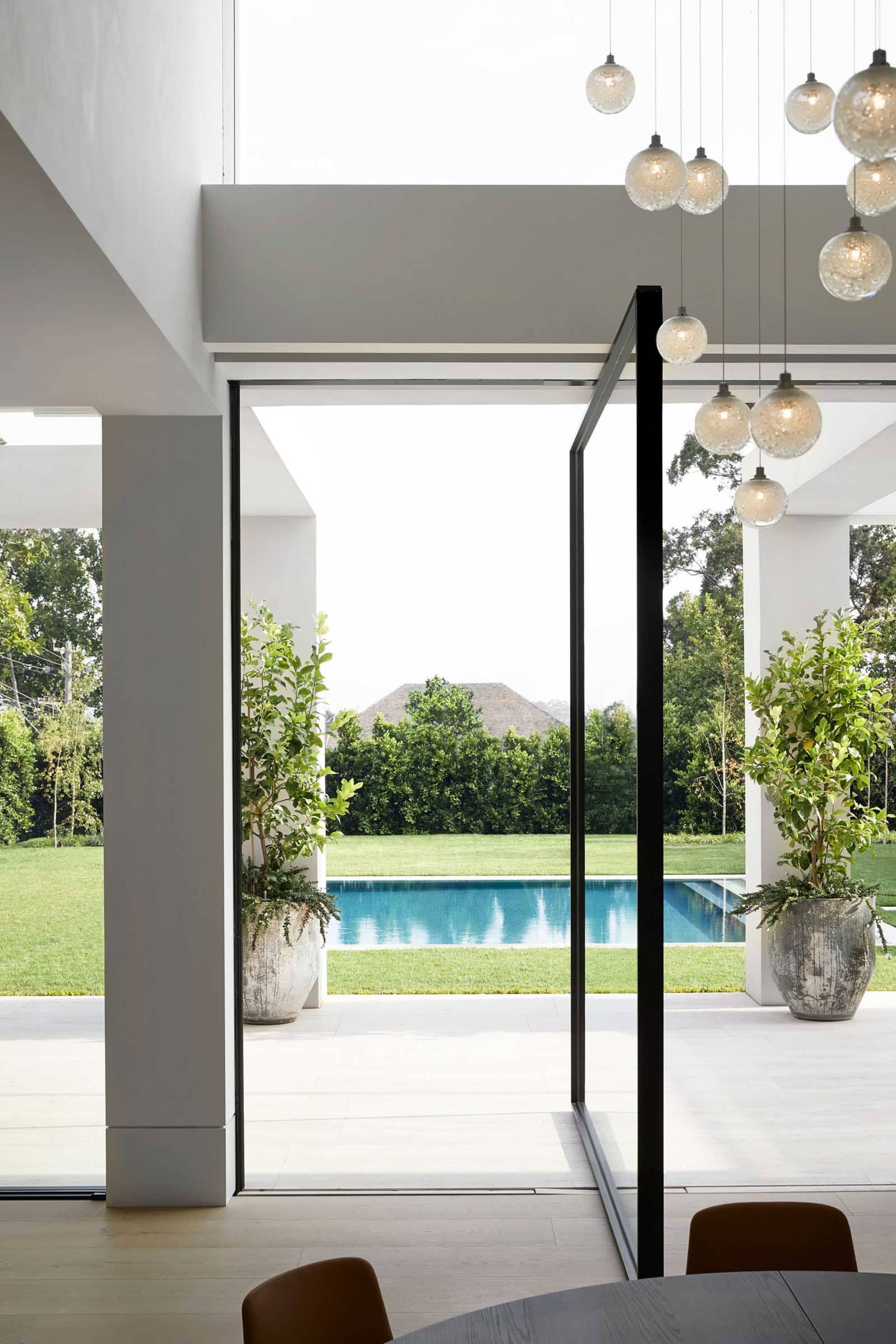 A modern outdoor living space with a large pool surrounded by green grass, potted plants, and a relaxing atmosphere