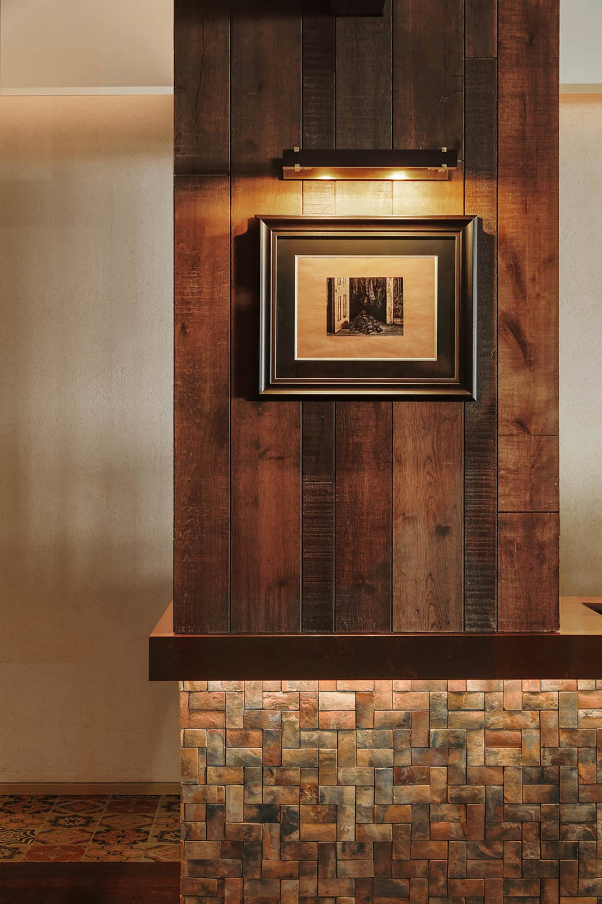 A black and white photograph of a wooden wall with a picture frame containing a forest scene, in a cozy and warm living area