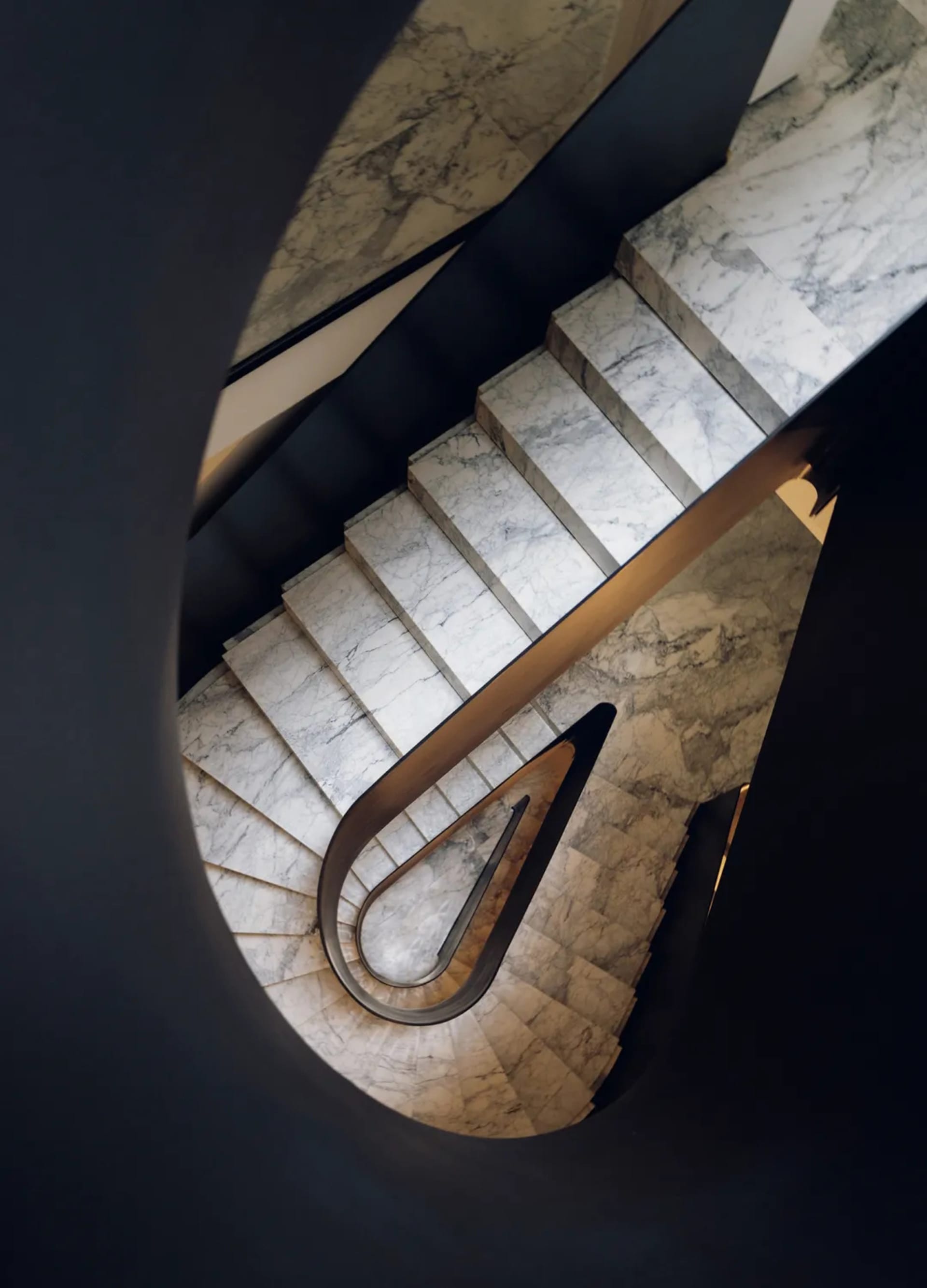 A black and white photograph of a curved marble staircase with a sophisticated and timeless appearance
