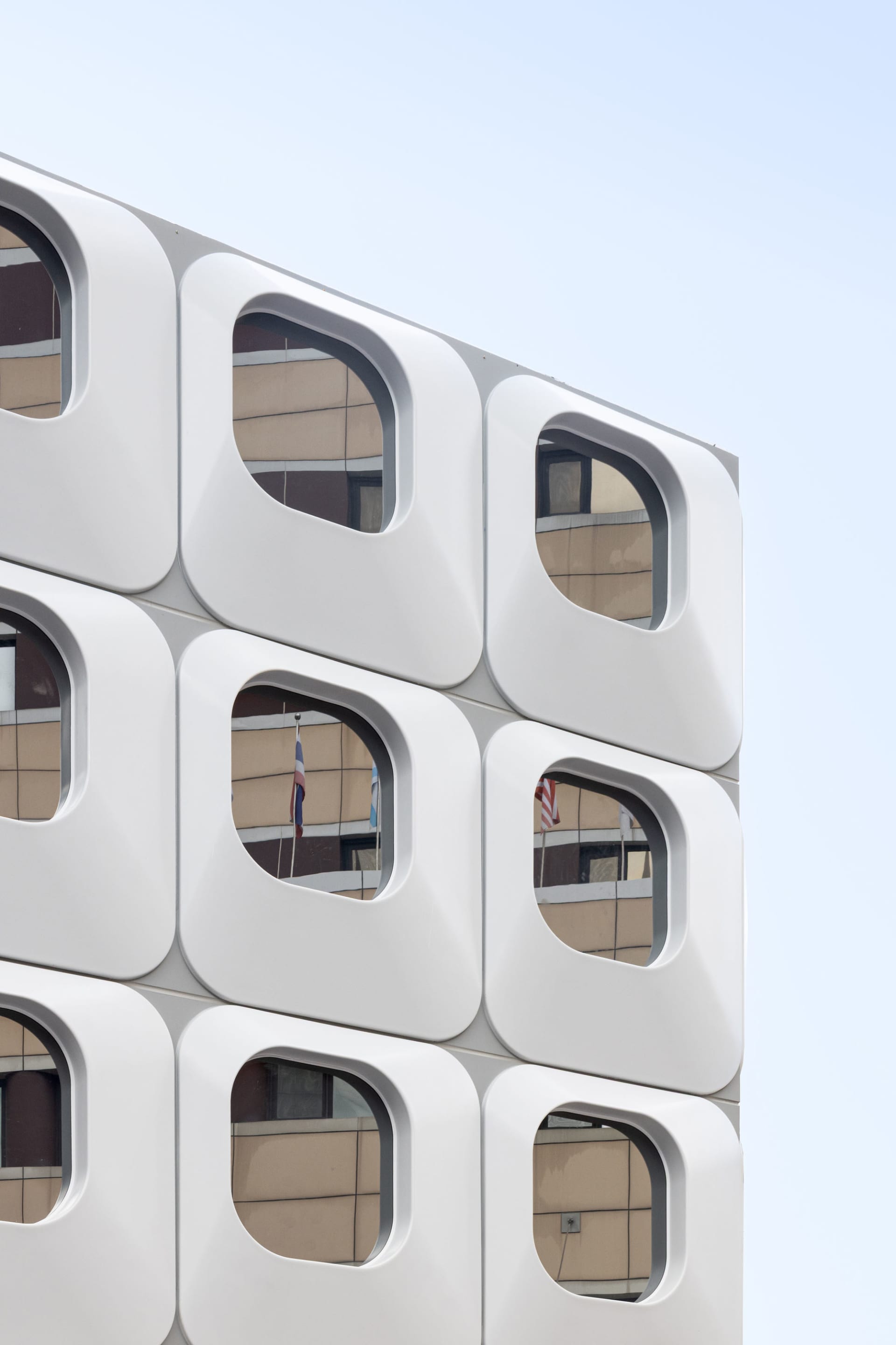 A large white building with a modern design, featuring a grid pattern of square windows and a predominantly white facade