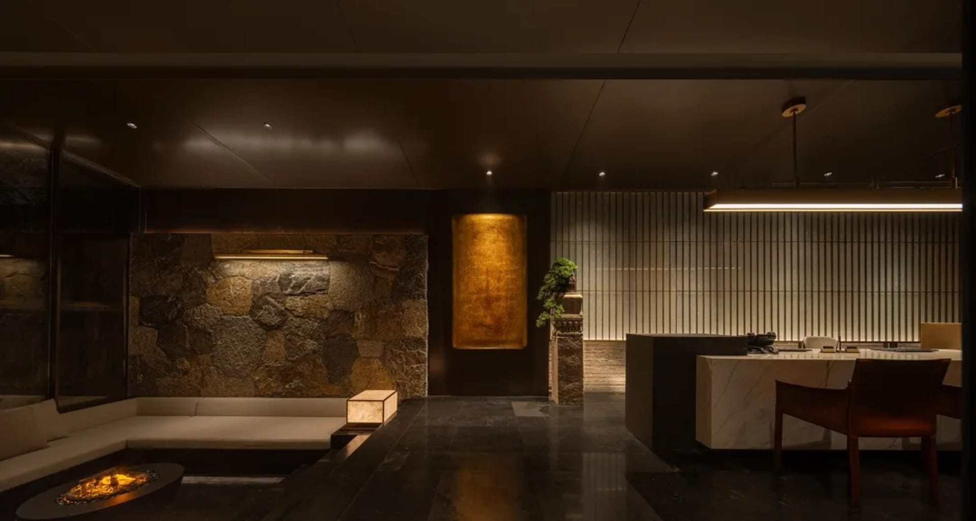 Cozy living room with stone walls, a stone floor, a couch, a bench, and a potted plant, lit by dim lighting