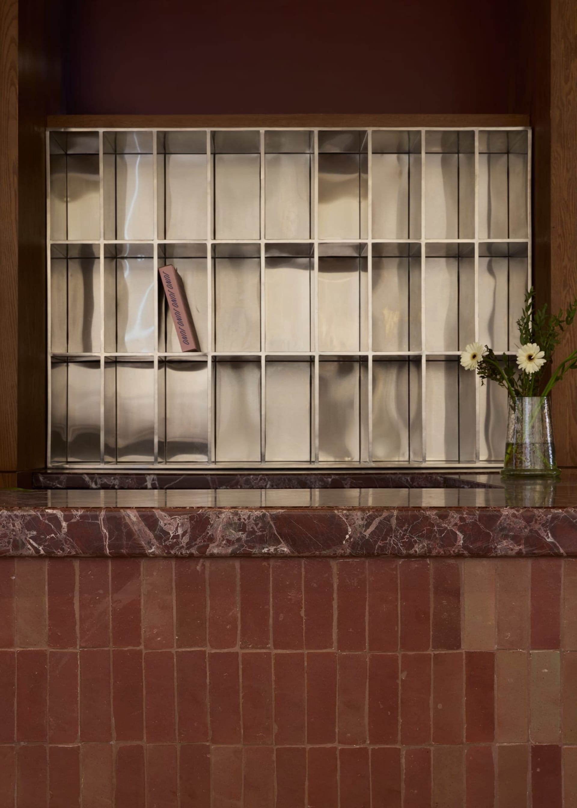 A marble countertop with a pink paperback book placed on it, set in a room with a wooden countertop and an elegant atmosphere