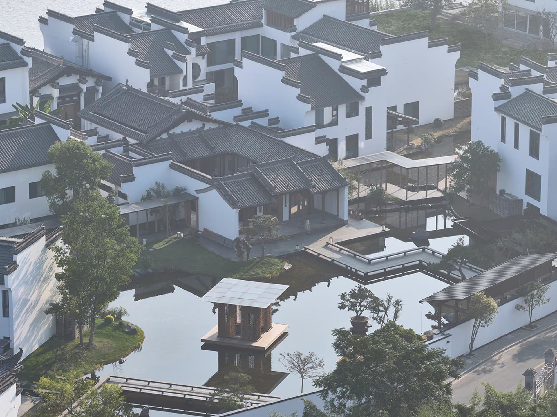 Serene traditional Chinese garden with a large white building, a pond, and a wooden deck with benches