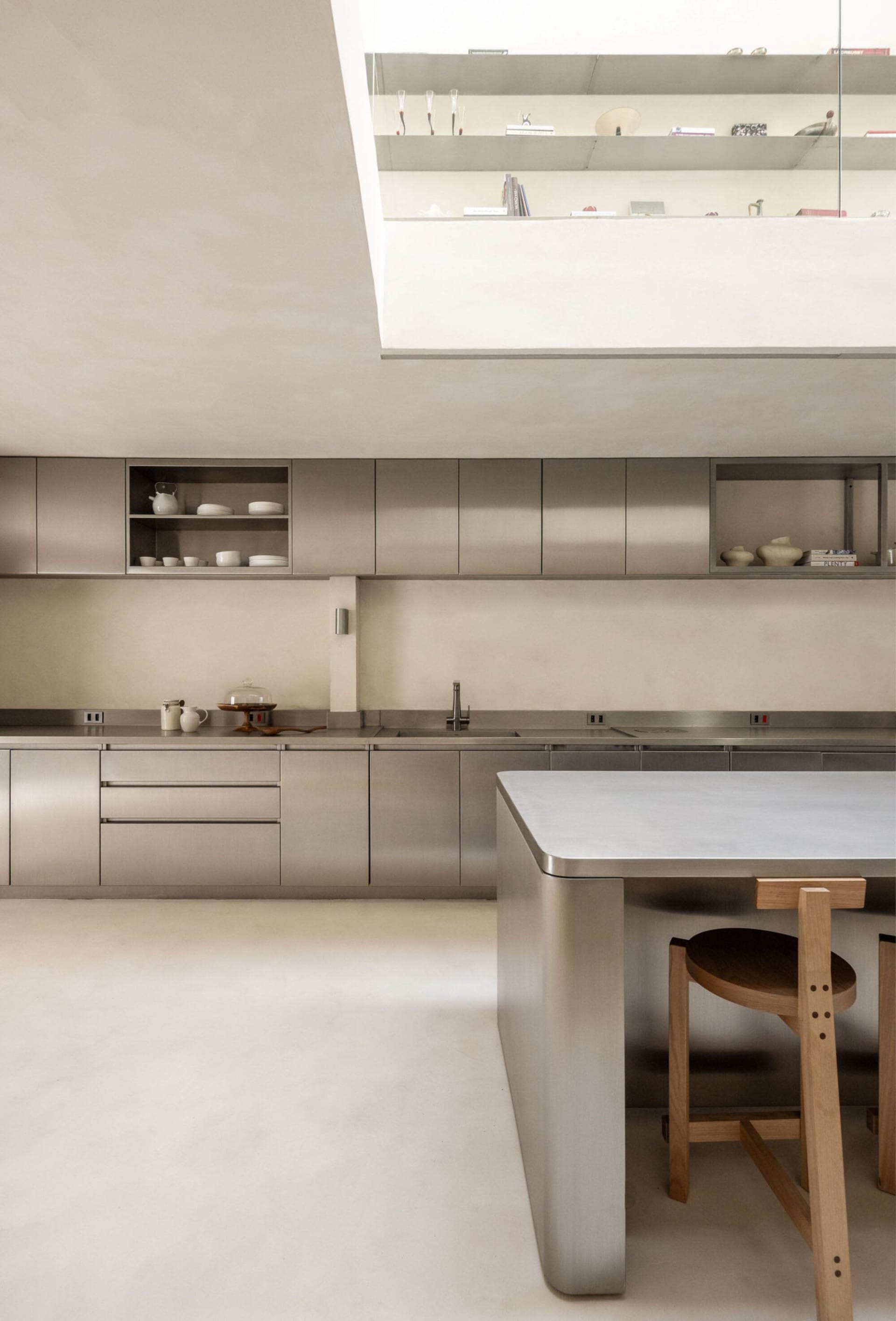 Modern kitchen with a stainless steel countertop and wooden table, featuring a sleek and inviting atmosphere with bright lighting