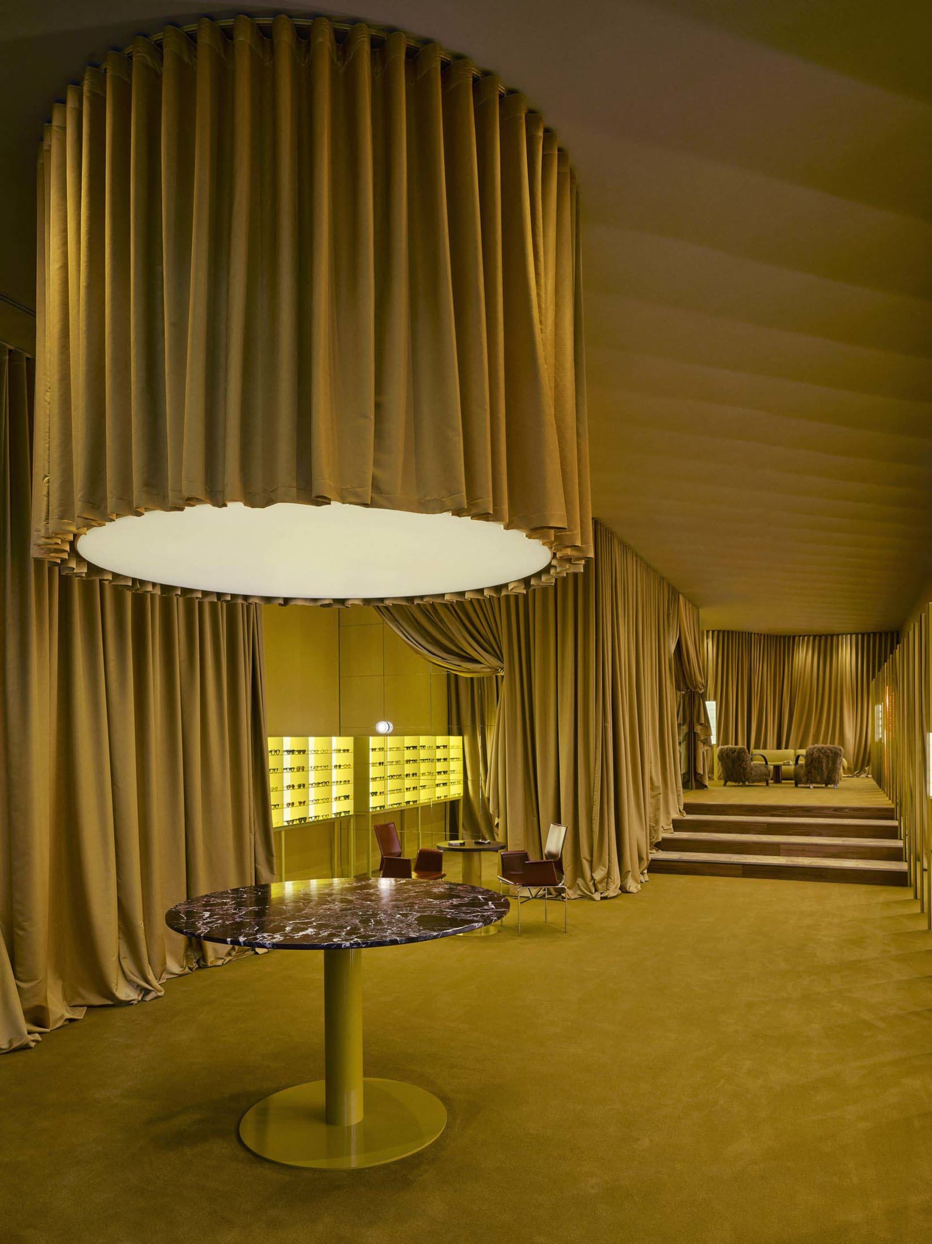 A modern dining room with a yellow color scheme, a dining table, chairs, a couch, a chair, and a large window with natural light