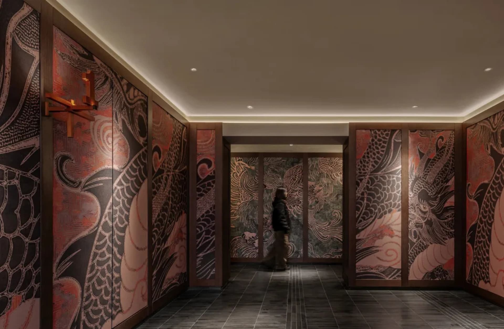 A calm and inviting hallway with Asian-style artwork on the walls, a person walking towards the camera, and a handbag visible in the scene