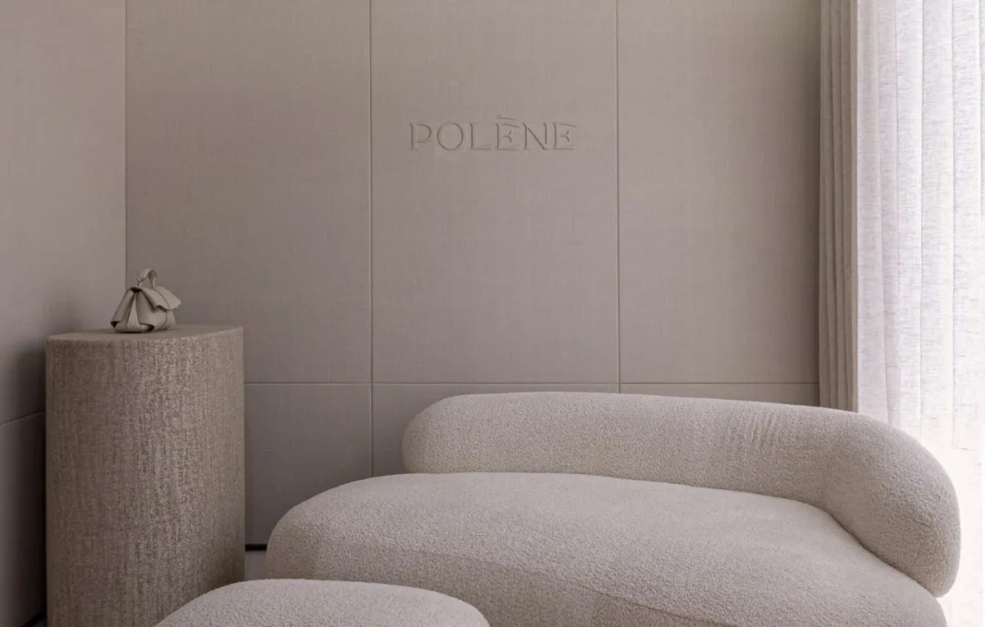 A modern living room with a white couch and a chair, soft lighting, and a logo on the wall