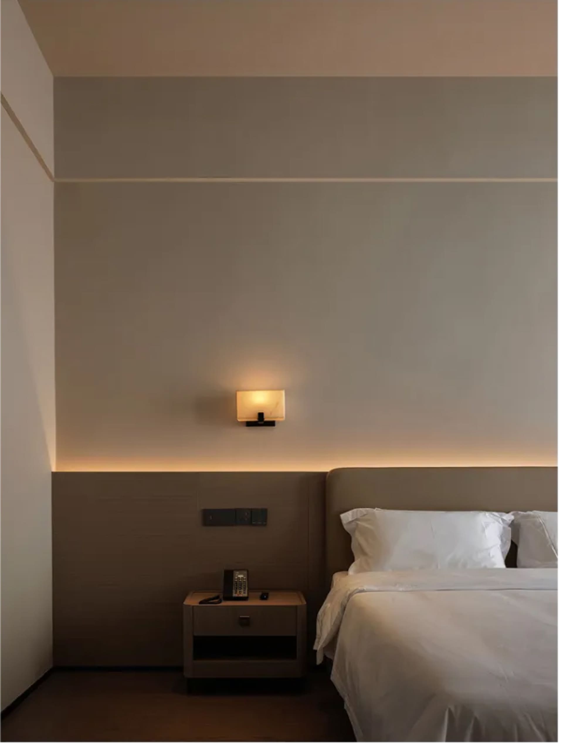 A well-lit bedroom with a wooden bed frame, nightstand, and lamp, creating a warm and inviting atmosphere