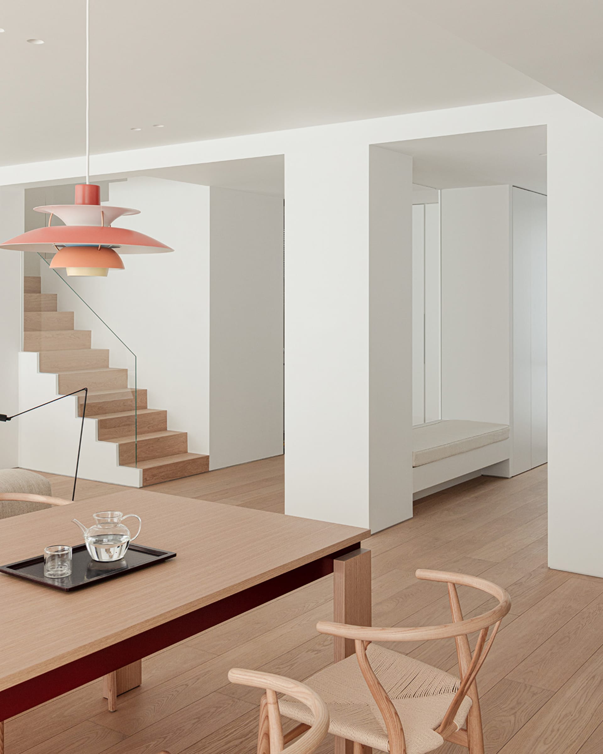 Comfortable living space with a wooden floor, dining table, couch, and staircase, well-lit by natural light through windows