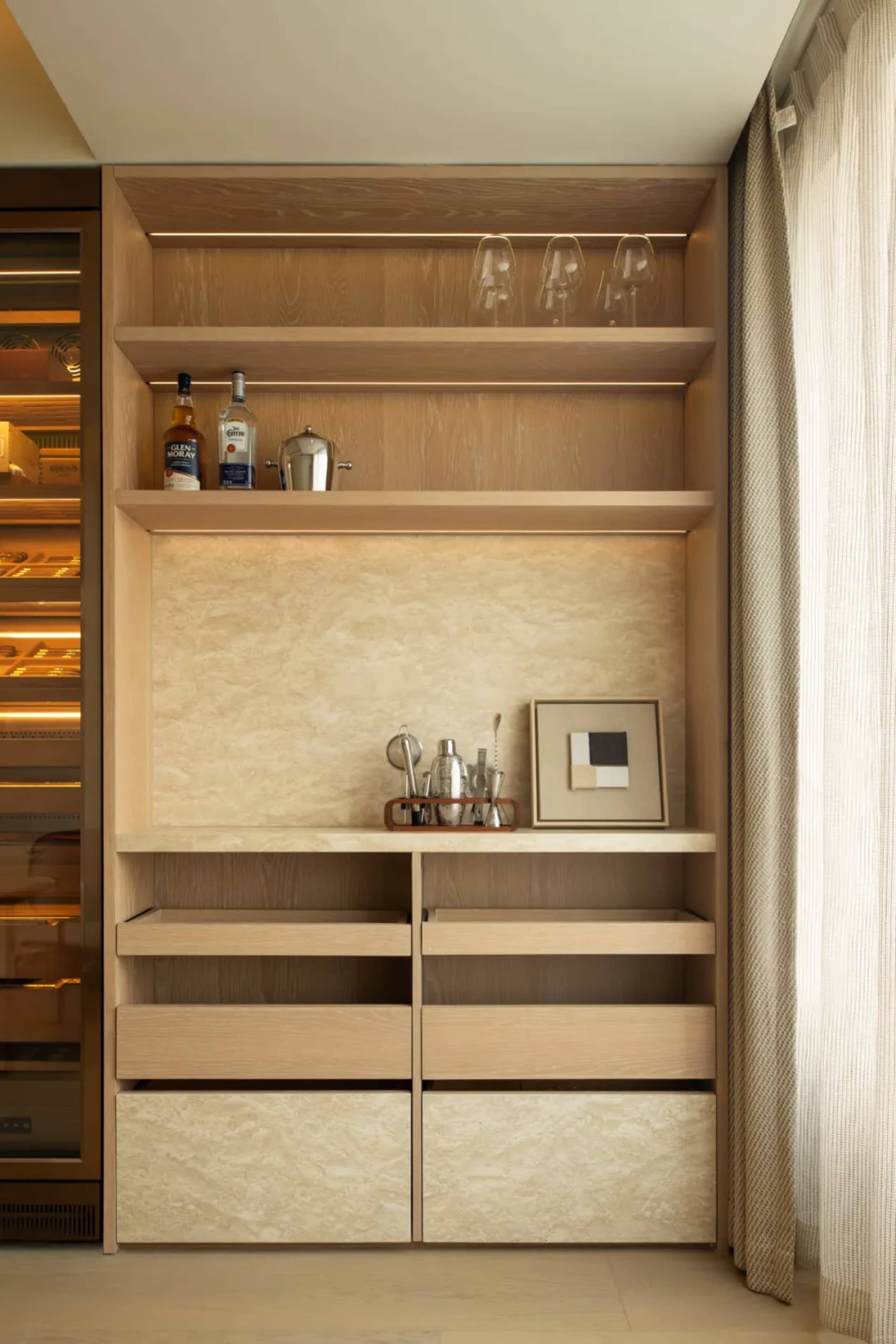 A modern kitchen with wooden cabinets and shelves, filled with various items, and well-lit for a warm atmosphere