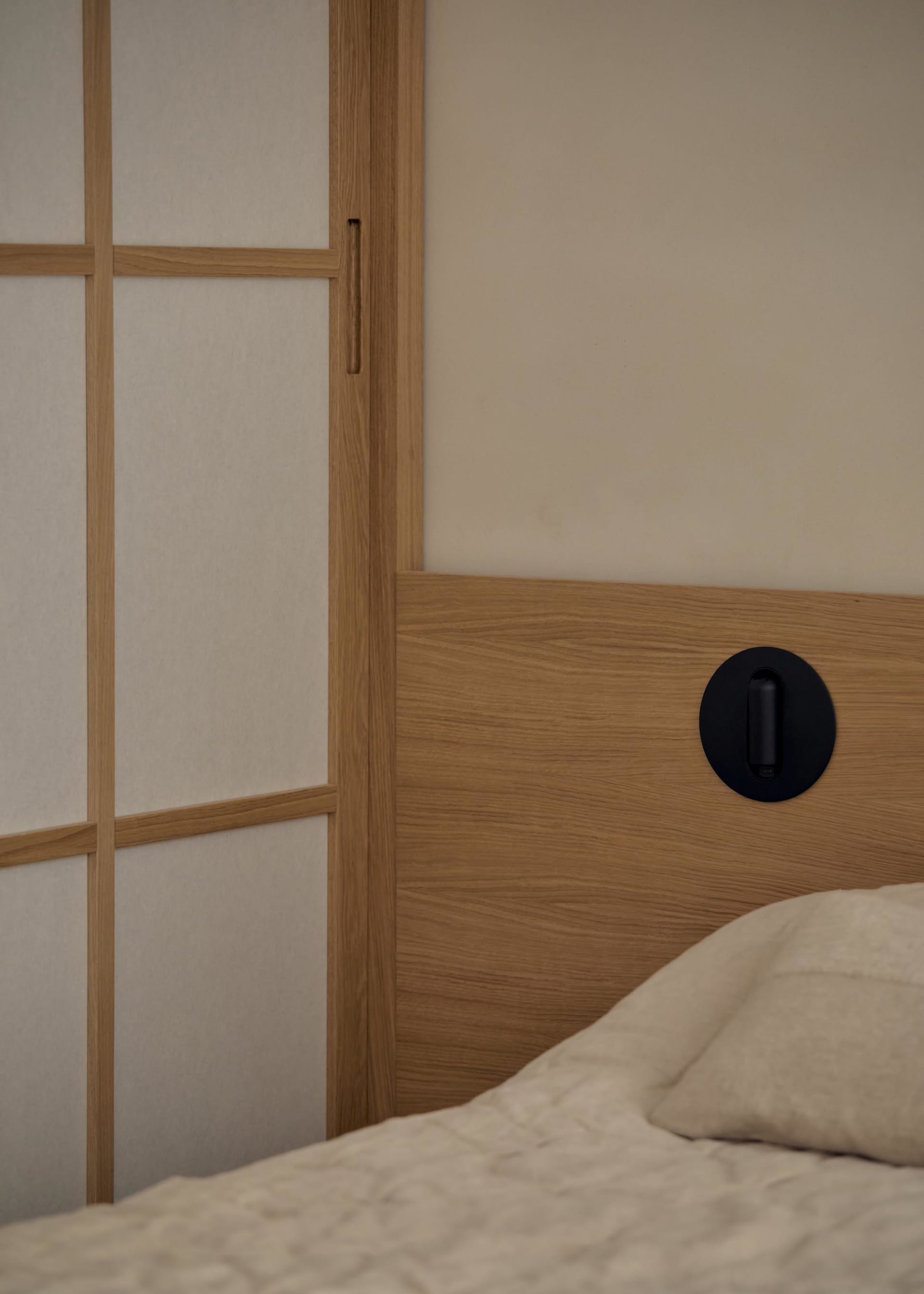 A well-lit bedroom with a wooden headboard, a white bed, and a wooden cabinet, creating a comfortable atmosphere