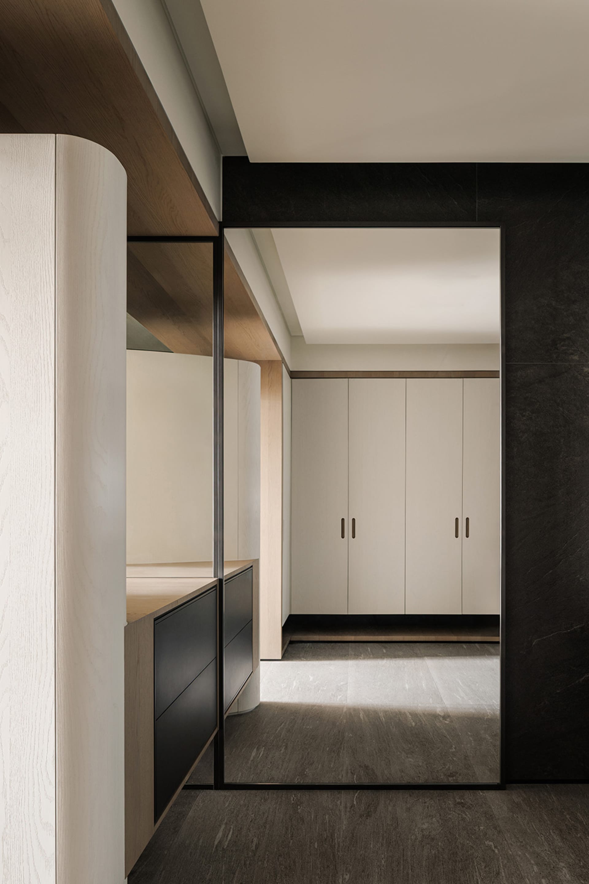 Modern kitchen and hallway with black cabinets, white countertops, and natural light from the doorway