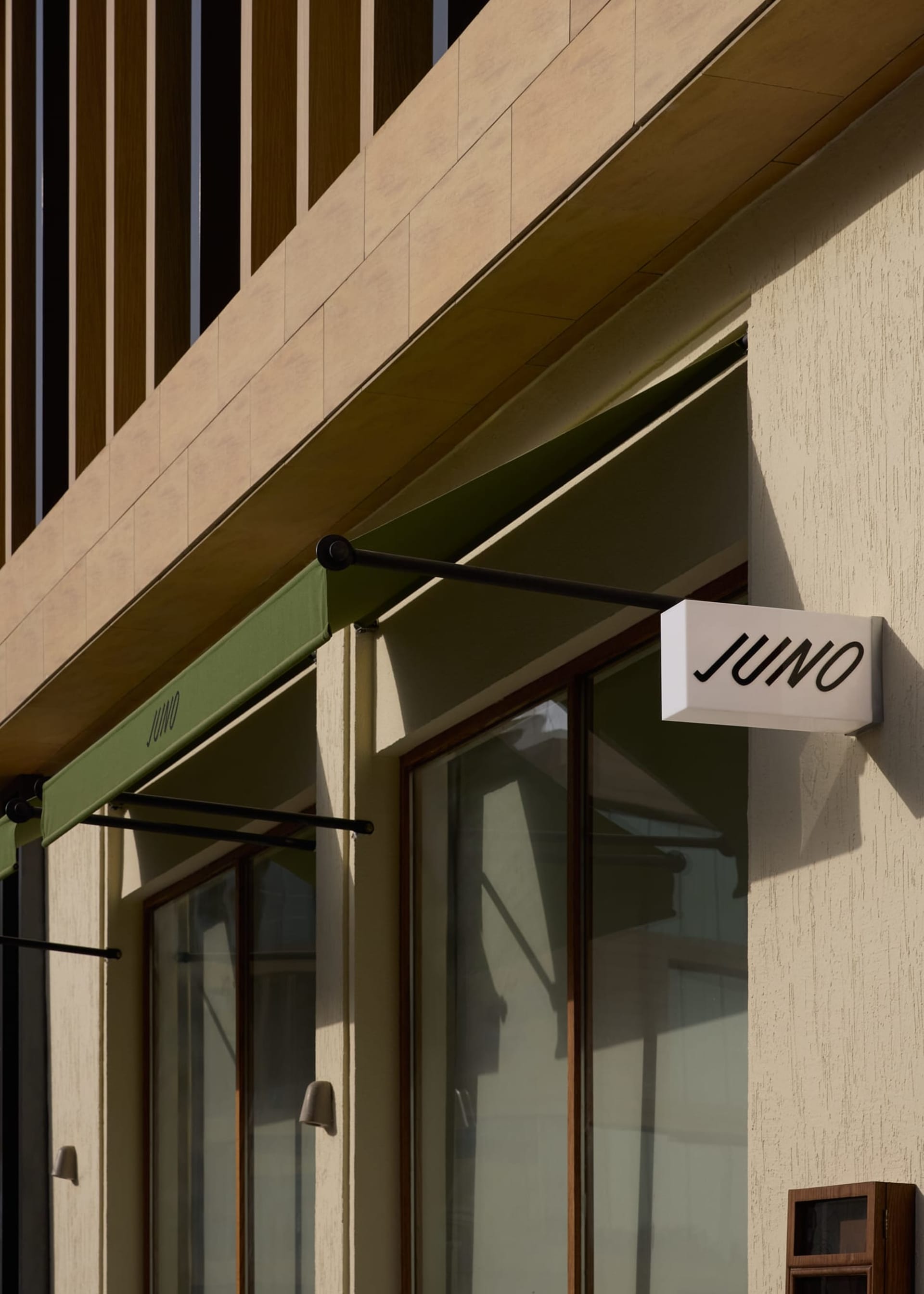 A modern storefront with a black awning, green trim, and natural light from the sun, creating a bright and inviting atmosphere