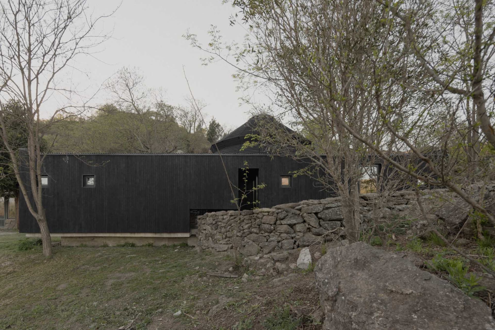 A small, traditional stone house with a black door and a simple design, captured in a black and white photograph from a low angle perspective