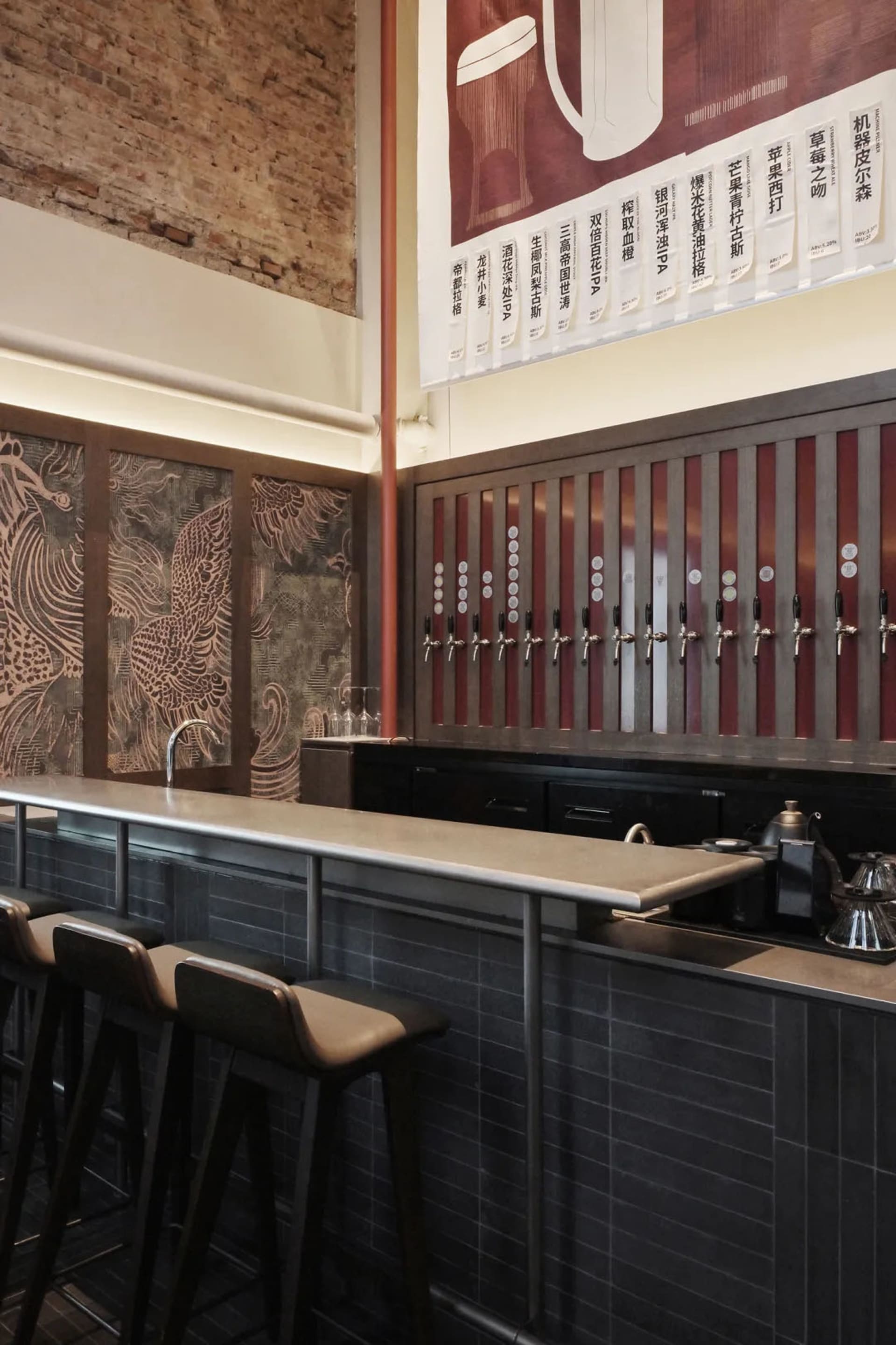 A modern bar with a metal counter, multiple beer taps, and comfortable seating, set in a well-lit atmosphere