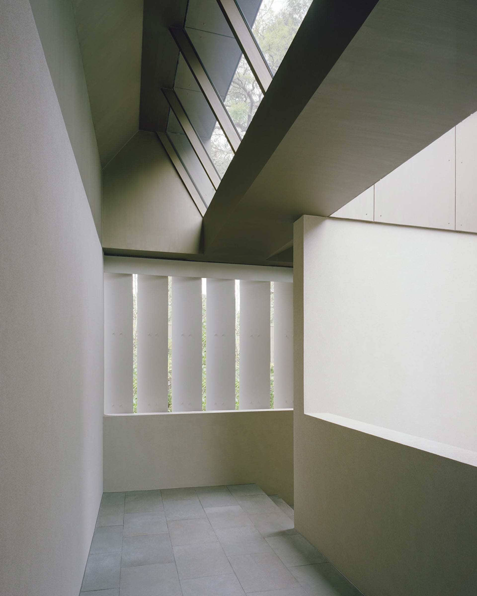 A calm and spacious lobby with a concrete wall and a large window allowing natural light to enter the space