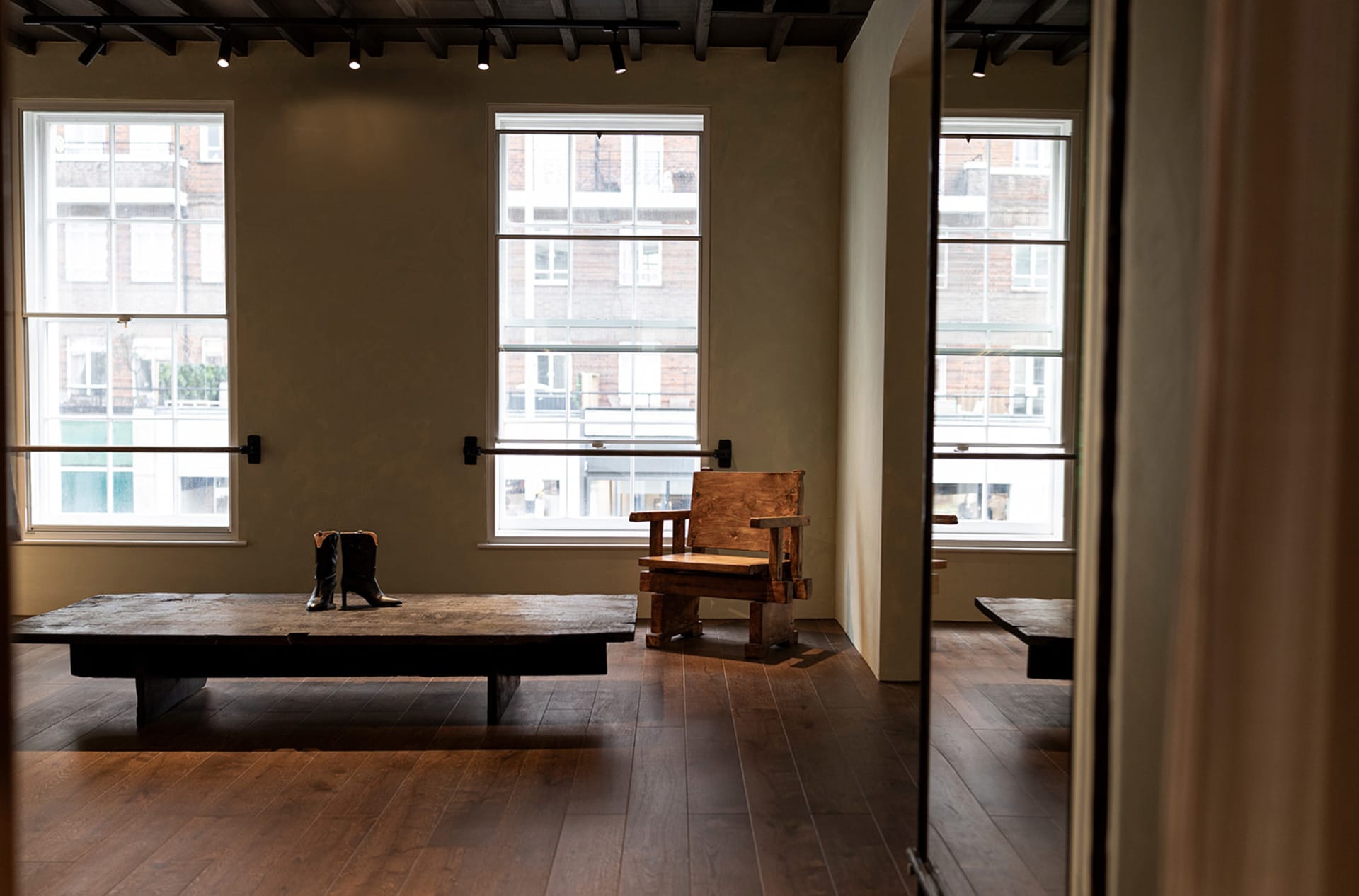 Warm and inviting living room with a wooden floor, a wooden table, a bench, and a large window allowing natural light to enter