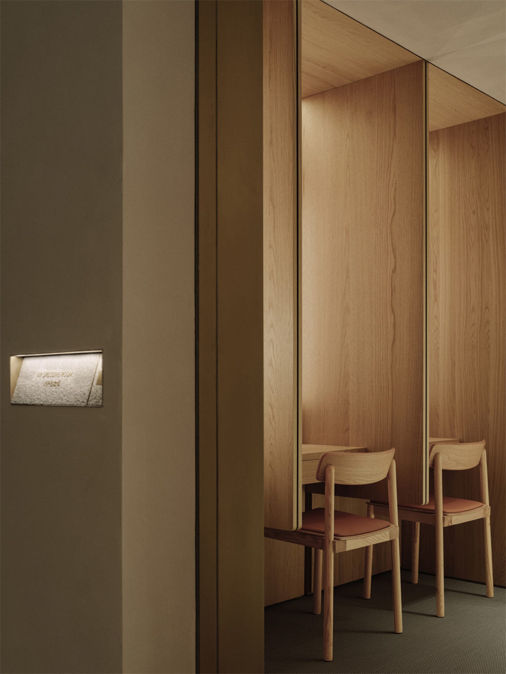 A bright and welcoming hallway with a doorway leading to a room with three wooden chairs and a wooden interior, illuminated by natural light