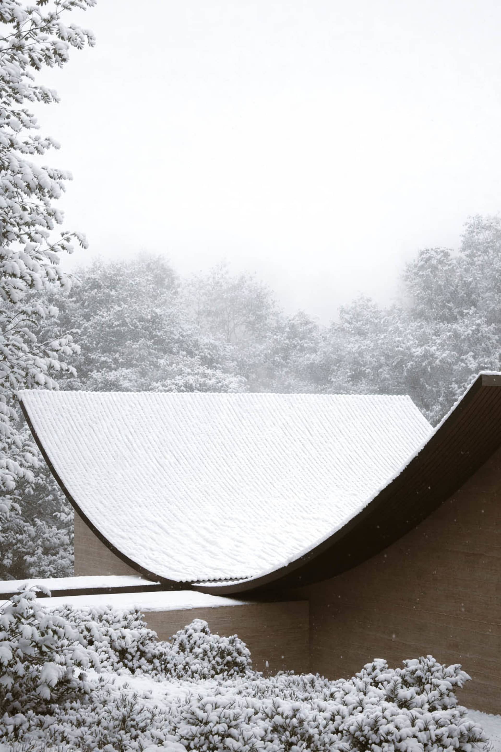 A serene winter scene of a church with a brown roof covered in snow, surrounded by trees