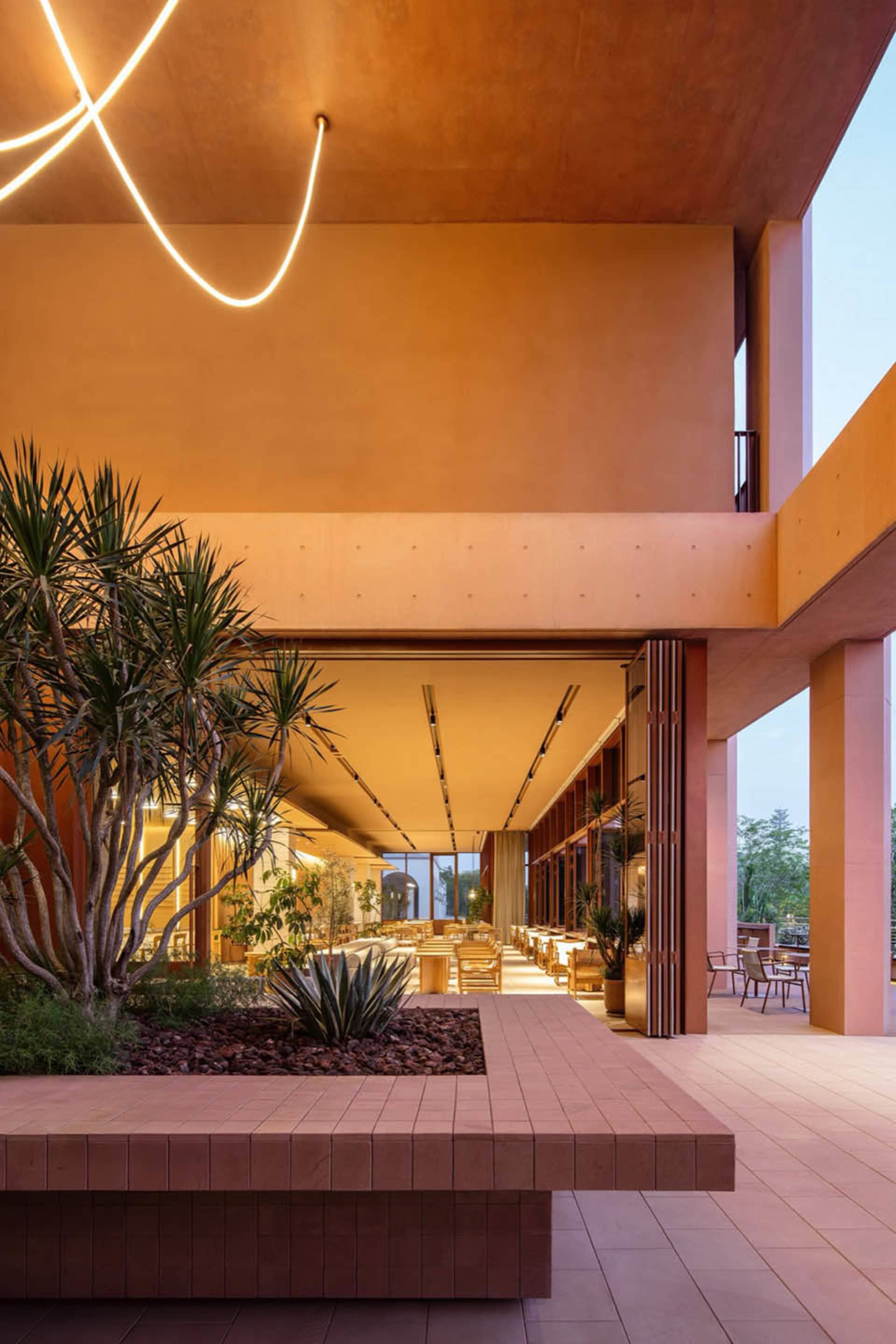 Inviting dining and lounge space with a pink exterior, multiple chairs, dining tables, a couch, and a warm color palette
