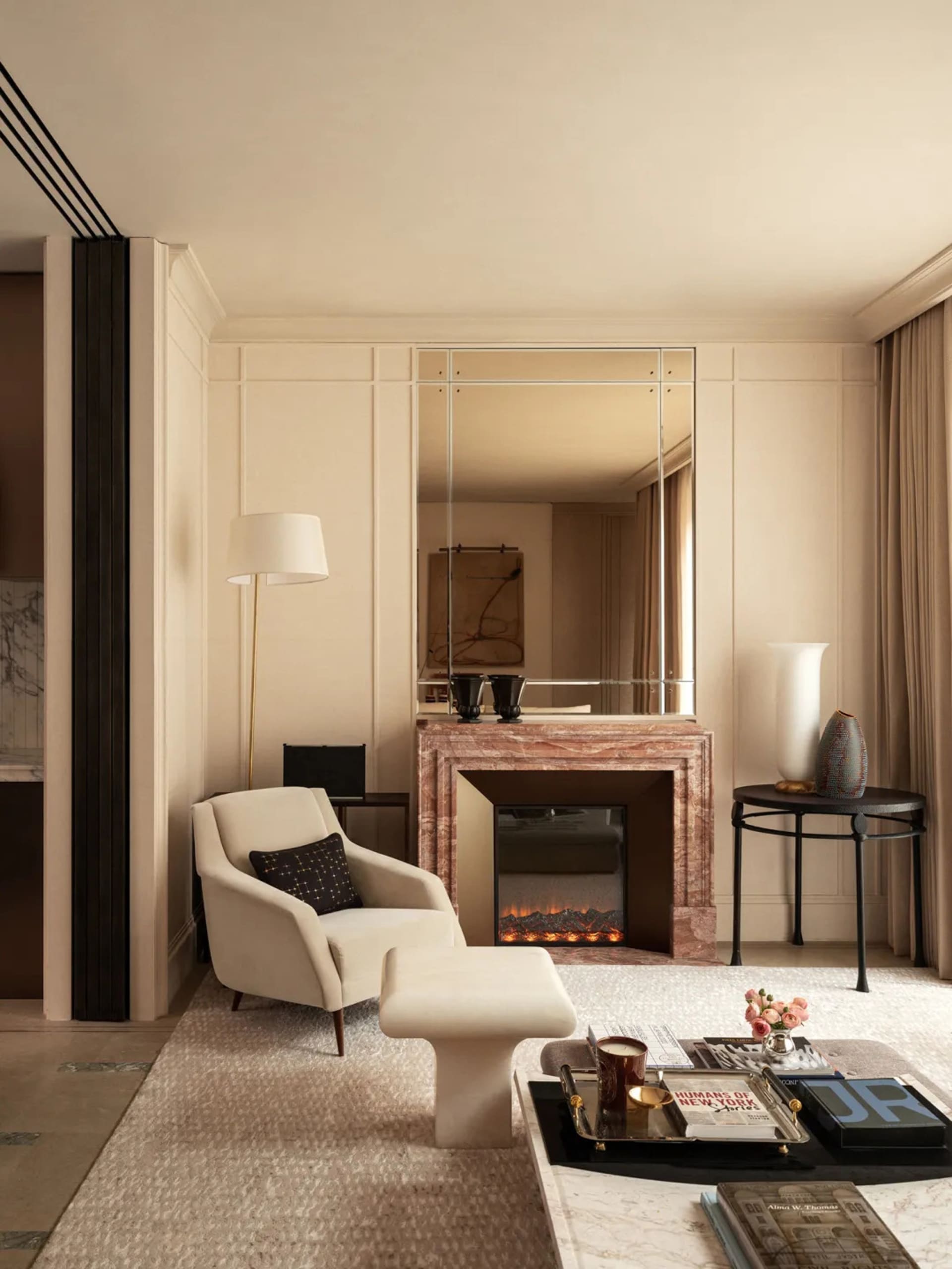 Cozy modern living space with a fireplace, a couch, a chair, and a table, decorated with a vase, a bowl, and a book, with soft and warm lighting