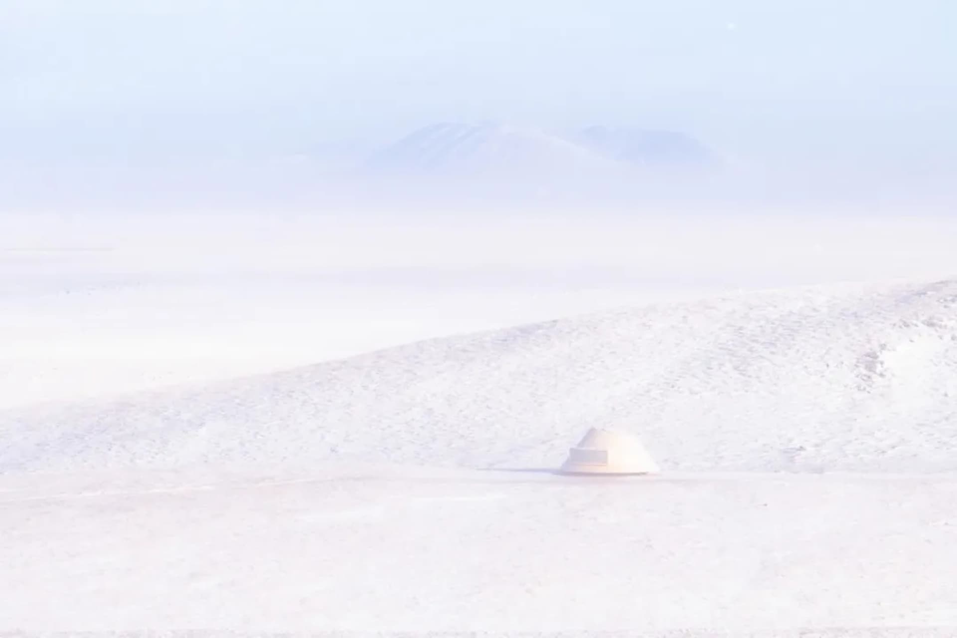 A dome-shaped structure stands out against a snowy backdrop, with a mix of white and grey material visible