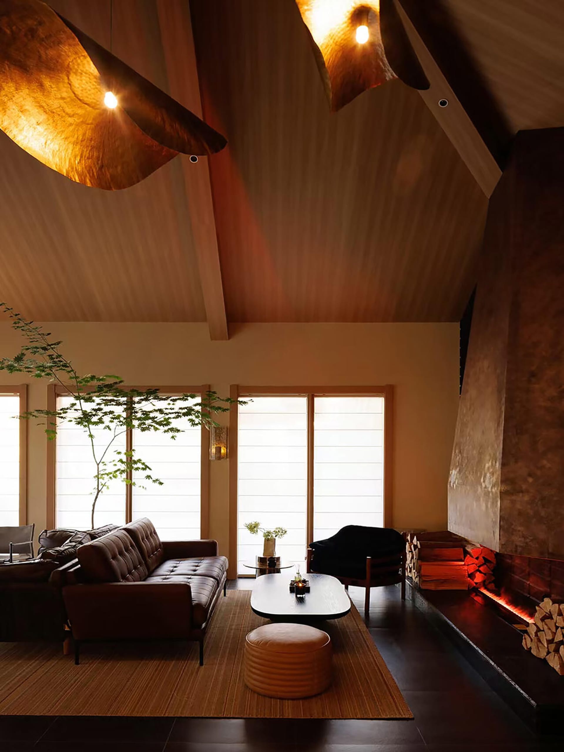 Cozy living room with a brown couch, a chair, and a fireplace, featuring a modern style with a mix of natural and artificial lighting