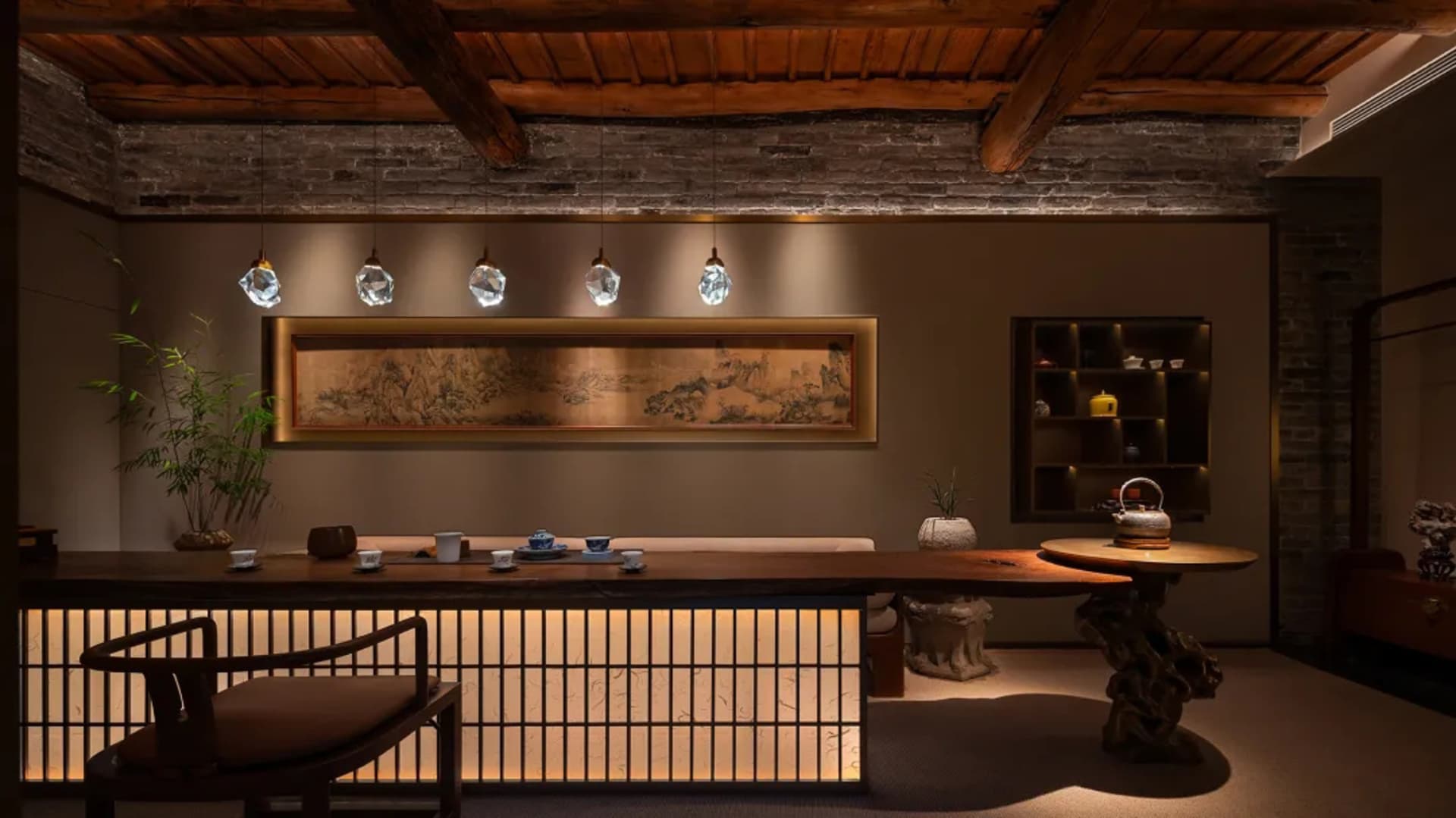 Cozy dining room with a wooden floor, table, and chairs, featuring a counter and a wall with a painting, with dim lighting creating an intimate ambiance