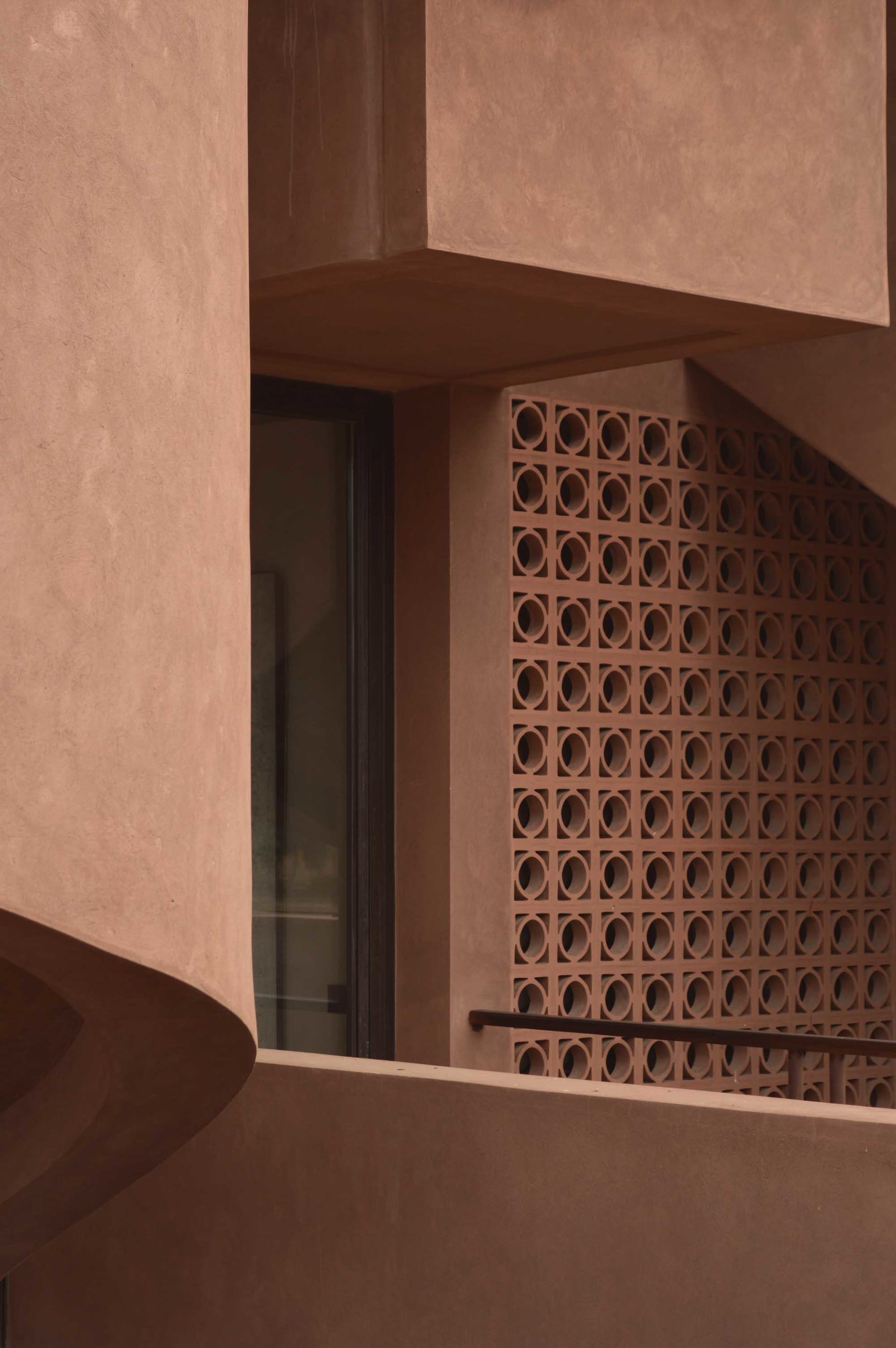 A brown building with a brick exterior, featuring a window with a view of a staircase, set in a natural outdoor environment with dark lighting