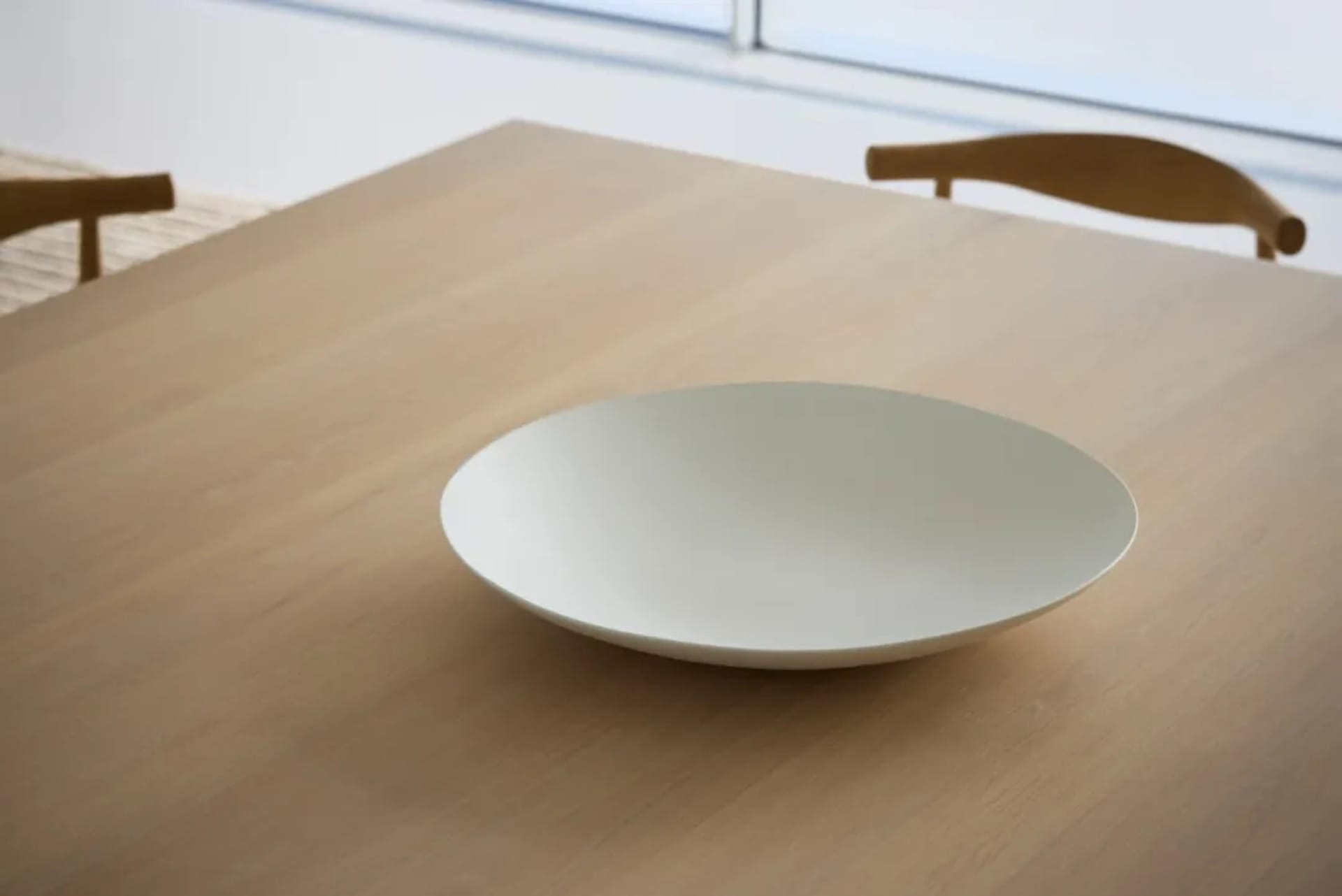 A wooden dining table with a white plate on it in a dining area