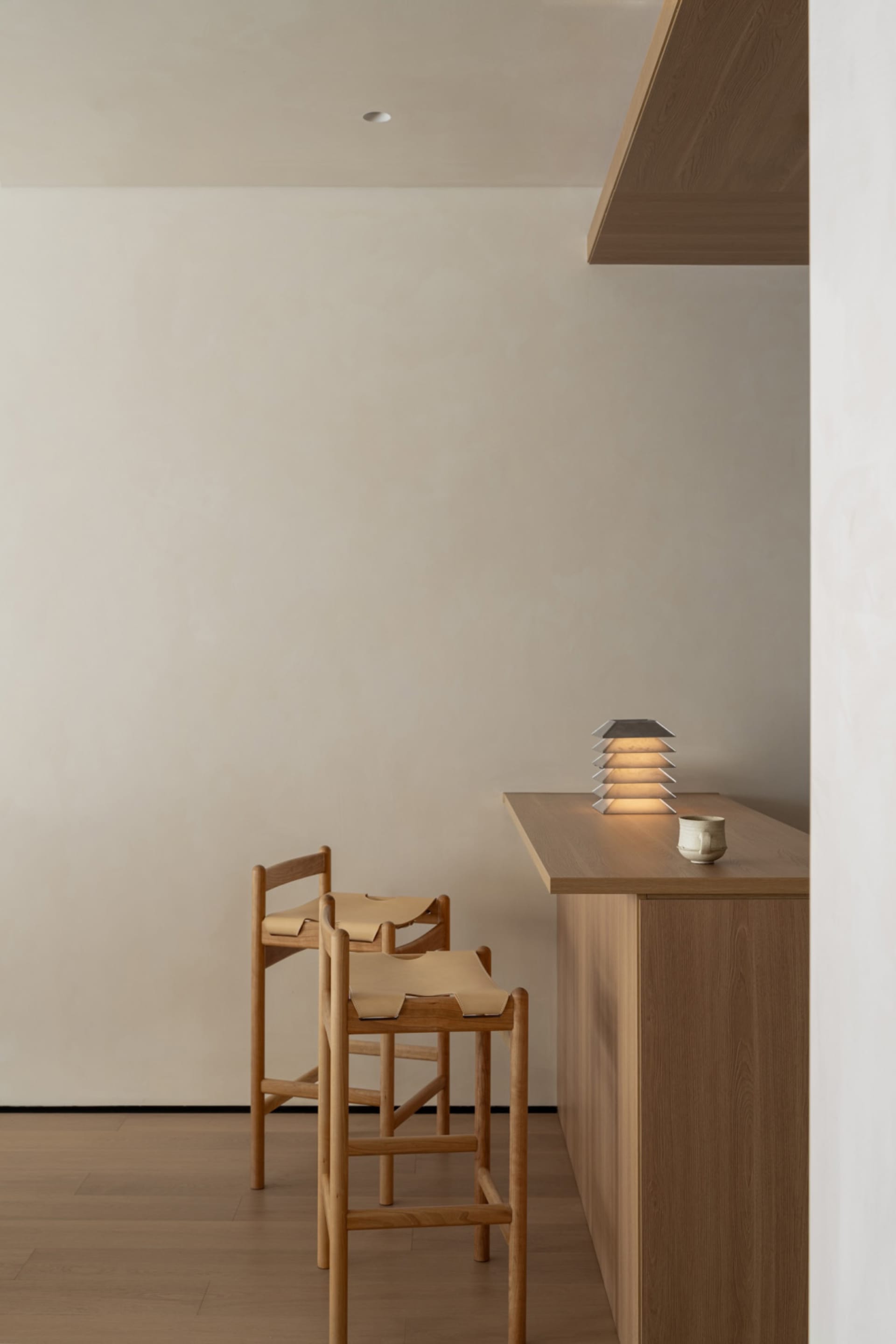 A kitchen or dining area with a wooden counter, chair, and overhead light, featuring a clean and organized space with a focus on functionality and simplicity