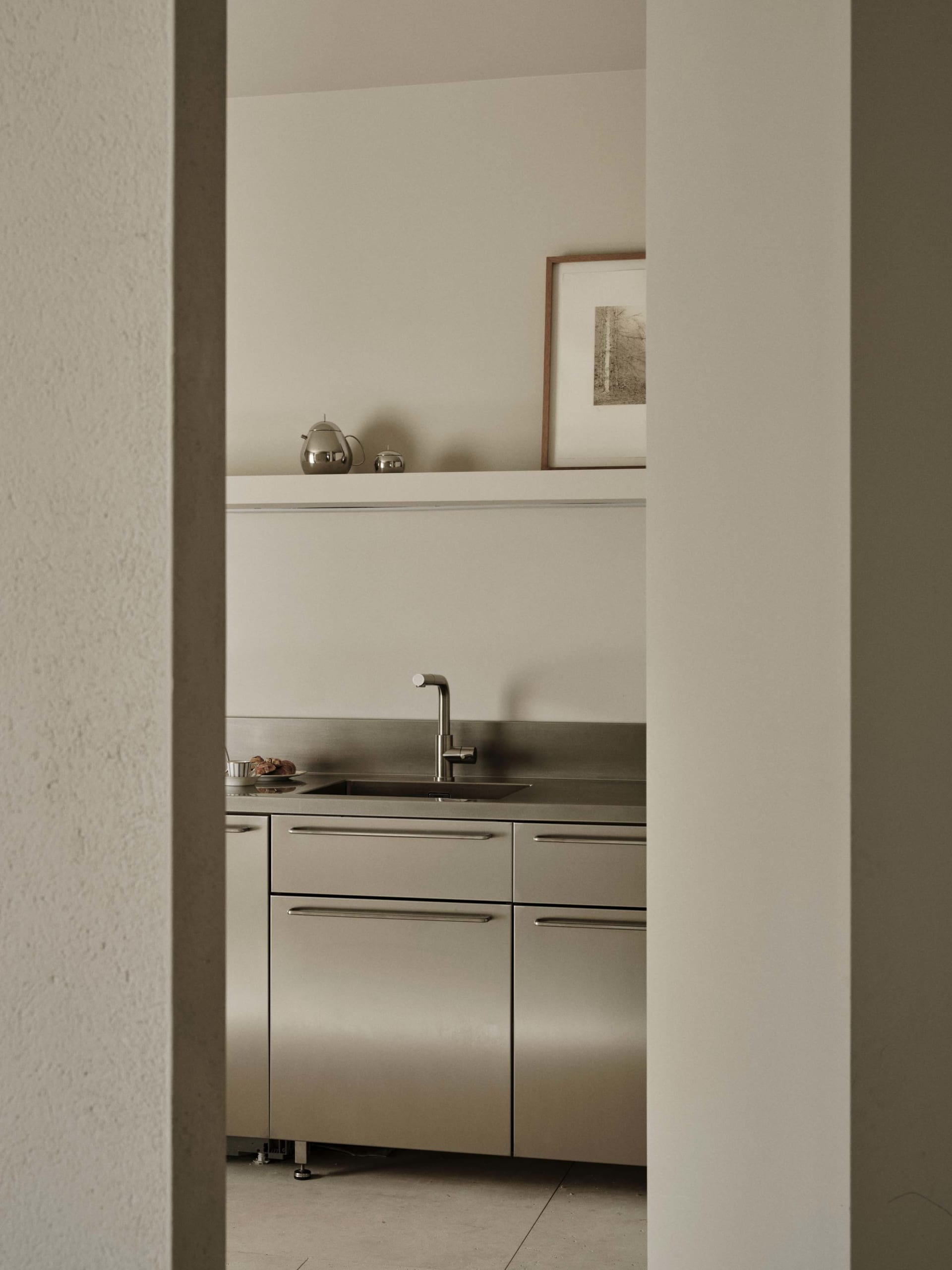A modern kitchen with a stainless steel sink, white refrigerator, and tile backsplash, featuring two cups on the countertop in a dimly lit space