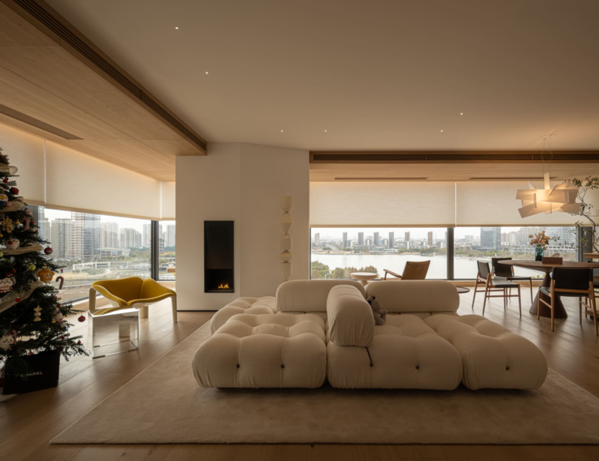 Cozy modern living space with a white couch, fireplace, dining table, and rug, well-lit with natural light from windows
