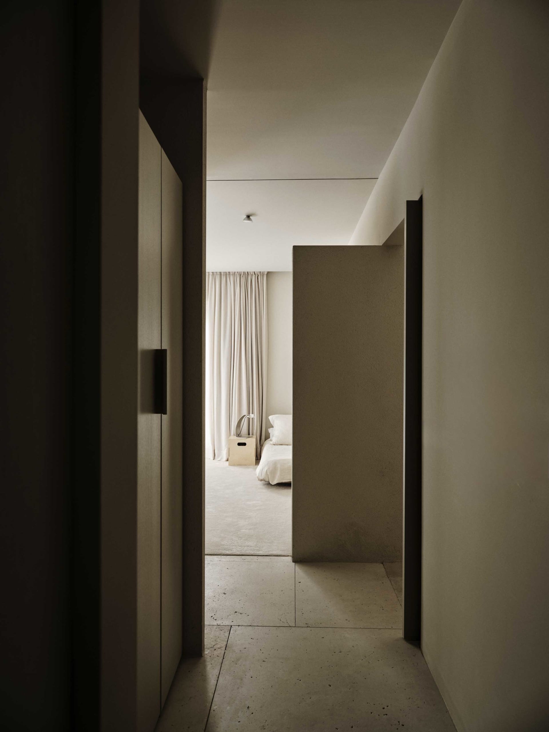 Dimly lit bedroom with a bed, chair, and handbag, creating a cozy atmosphere