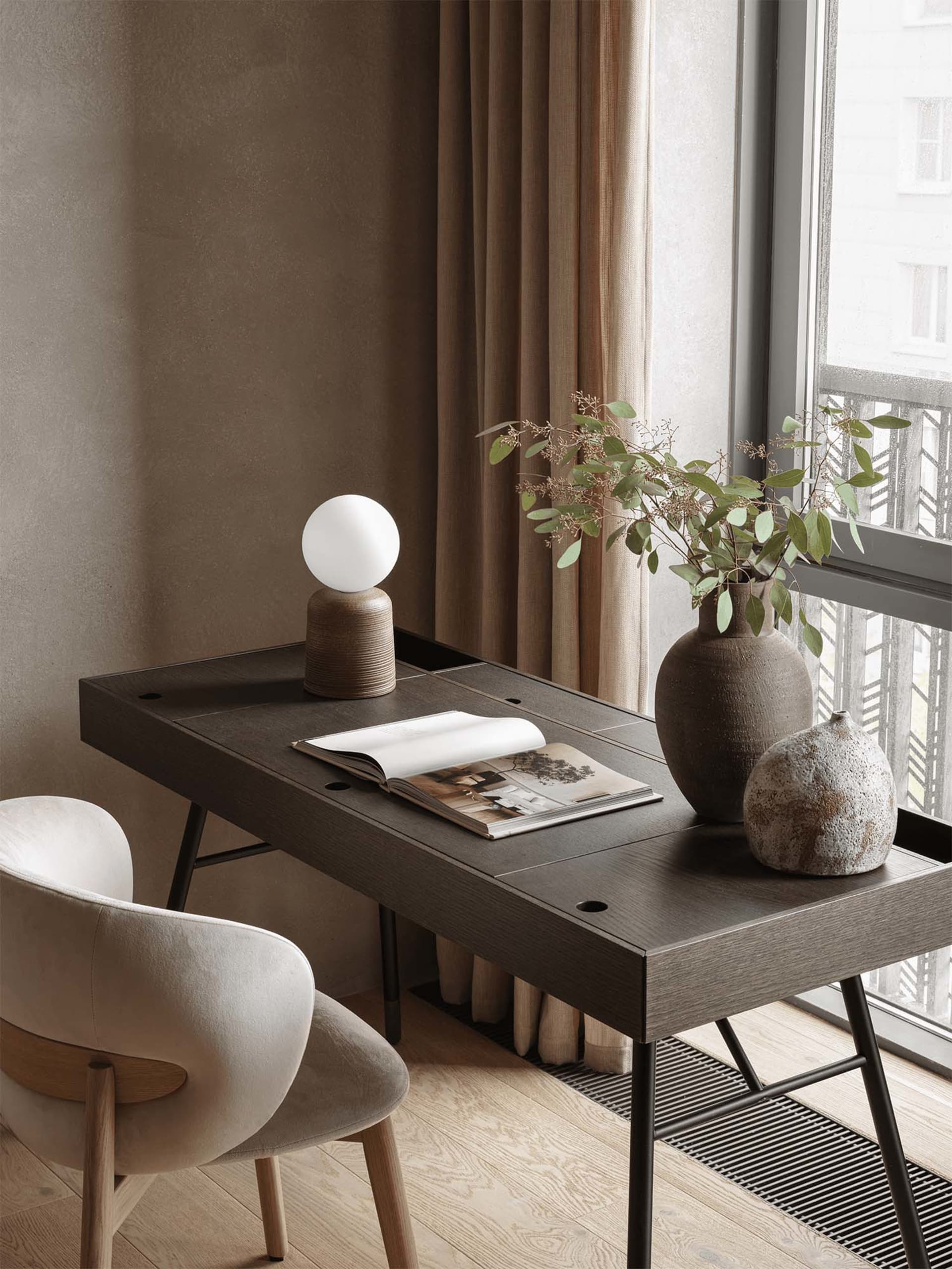 A modern living room with a wooden floor, a dining table, a chair, a potted plant, and a window with natural light