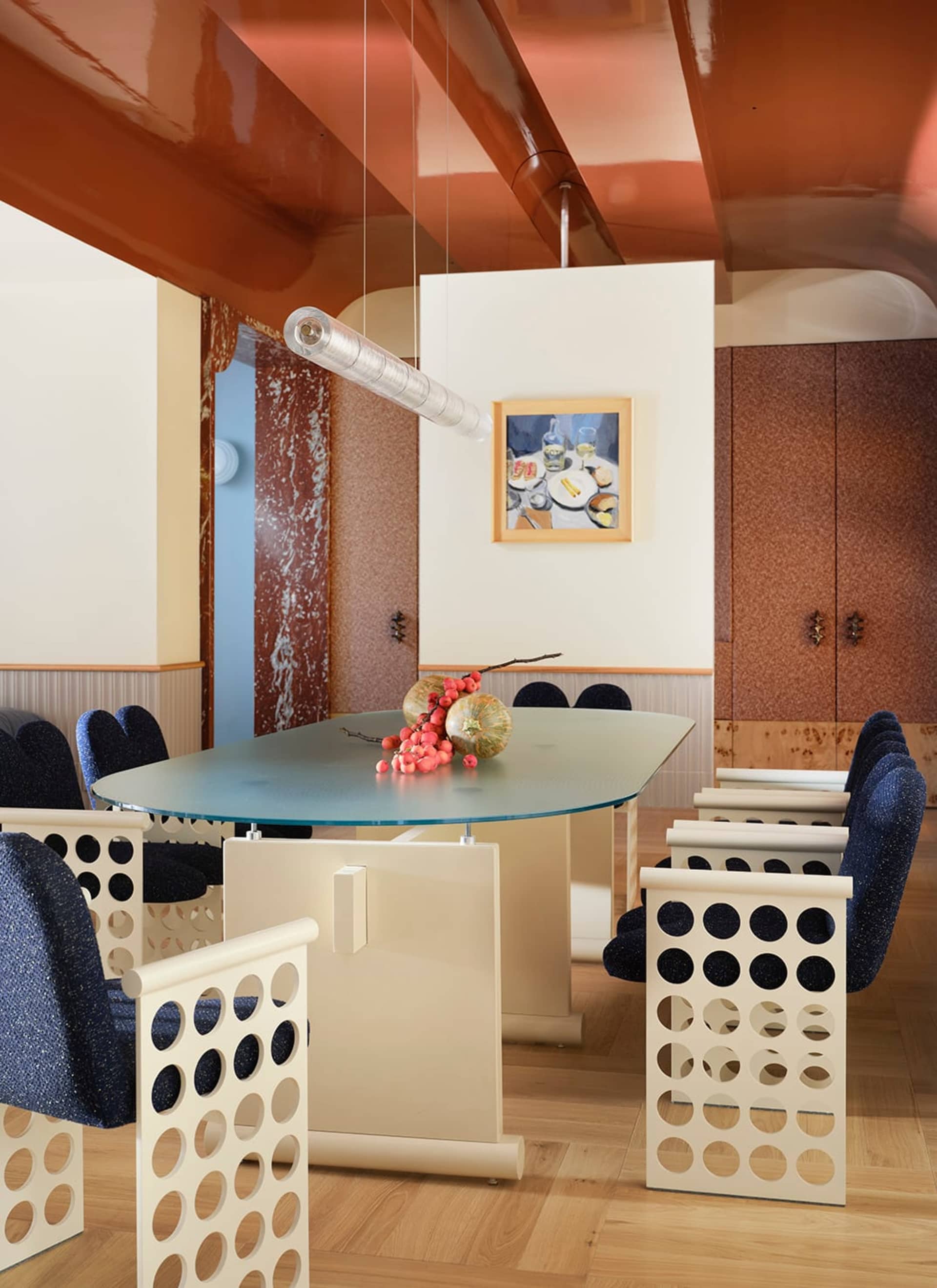 Dining room with a glass table and chairs, surrounded by a vase with fruit, in a modern space with natural lighting