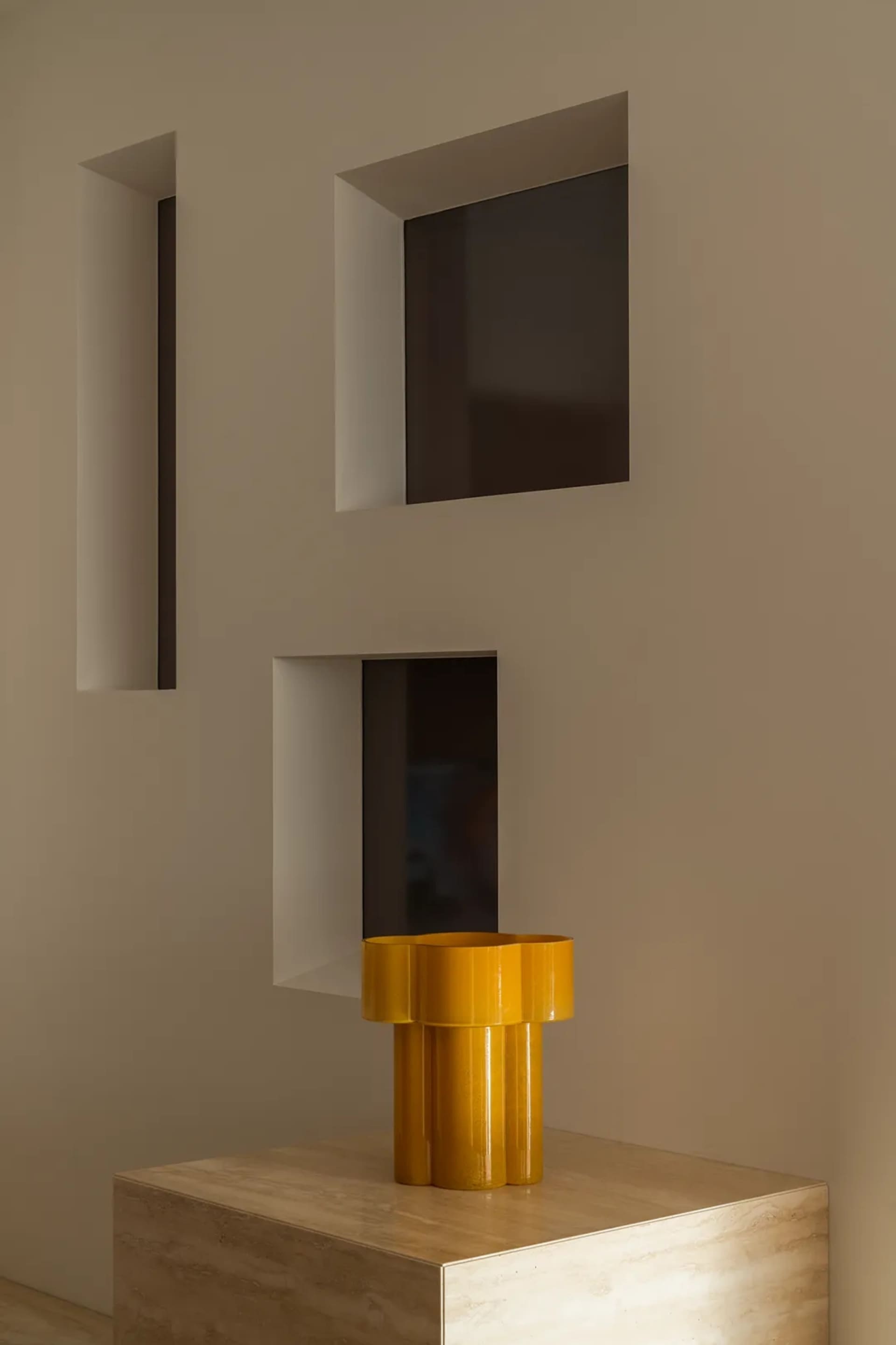 A dimly lit room with a brown wall, a window, and a yellow vase on a table