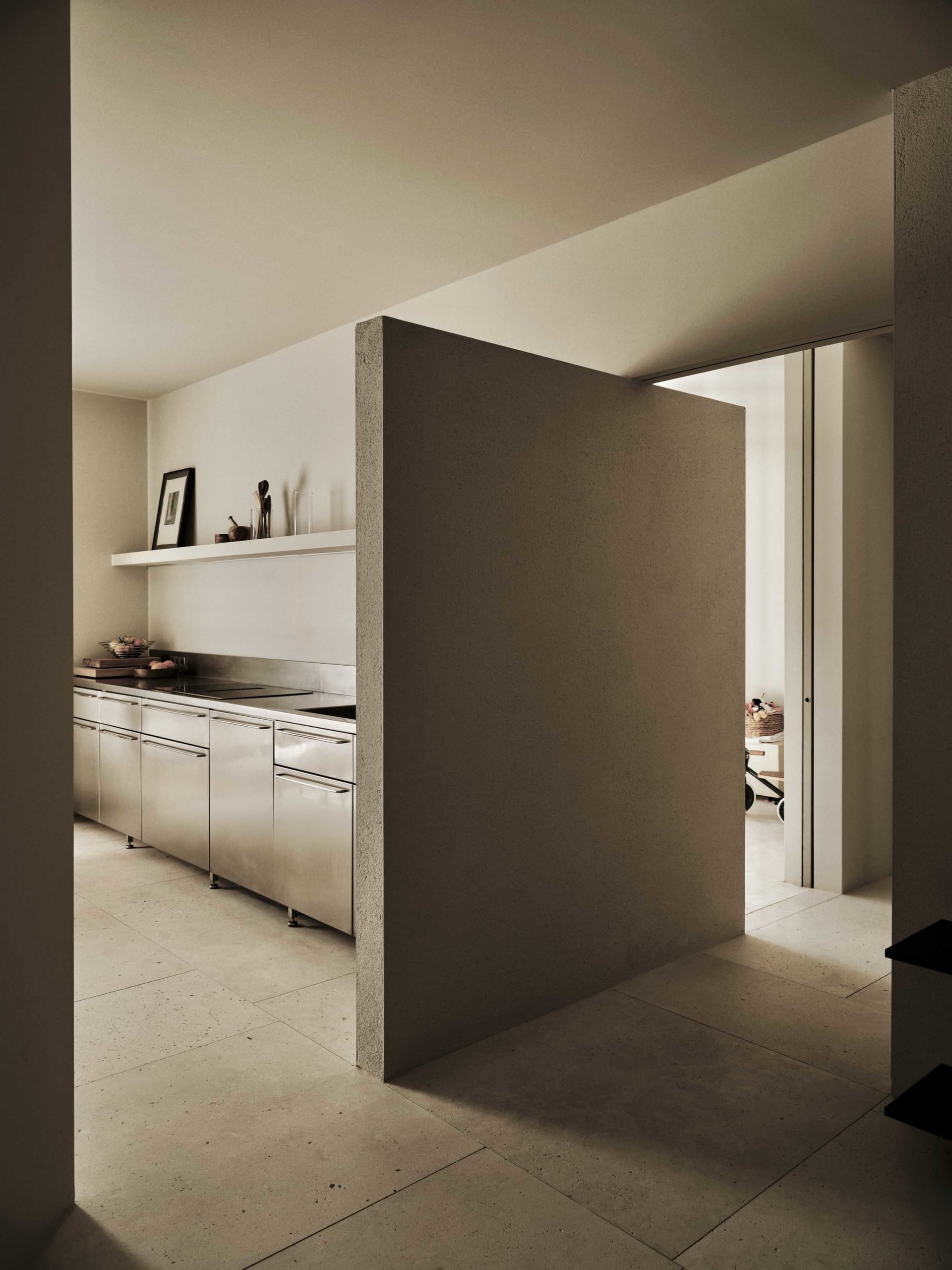 A modern kitchen with a white wall, marble countertop, stainless steel refrigerator, and dining table, lit dimly for a cozy atmosphere
