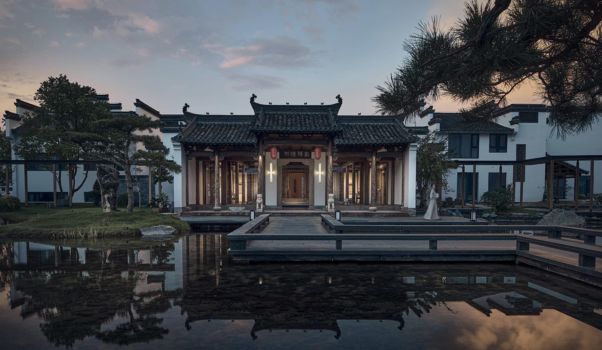 A large ornate building with a Chinese architectural style, featuring a pagoda-like structure and a stone roof, surrounded by a serene pond